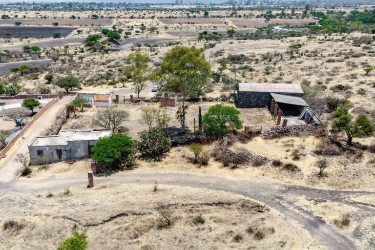 Rancho Guadalupe, aerial view of farm buildings, walls and trees beside a dirt road on the property, San Miguel de Allende