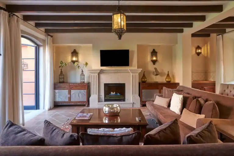 Rosewood Residence 7, living room with a fireplace, a dark sectional and a beamed ceiling, San Miguel de Allende