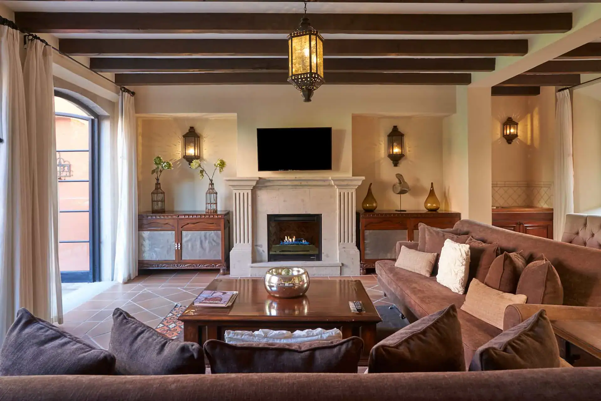 Rosewood Residence 7, living room with a fireplace, a dark sectional and a beamed ceiling, San Miguel de Allende