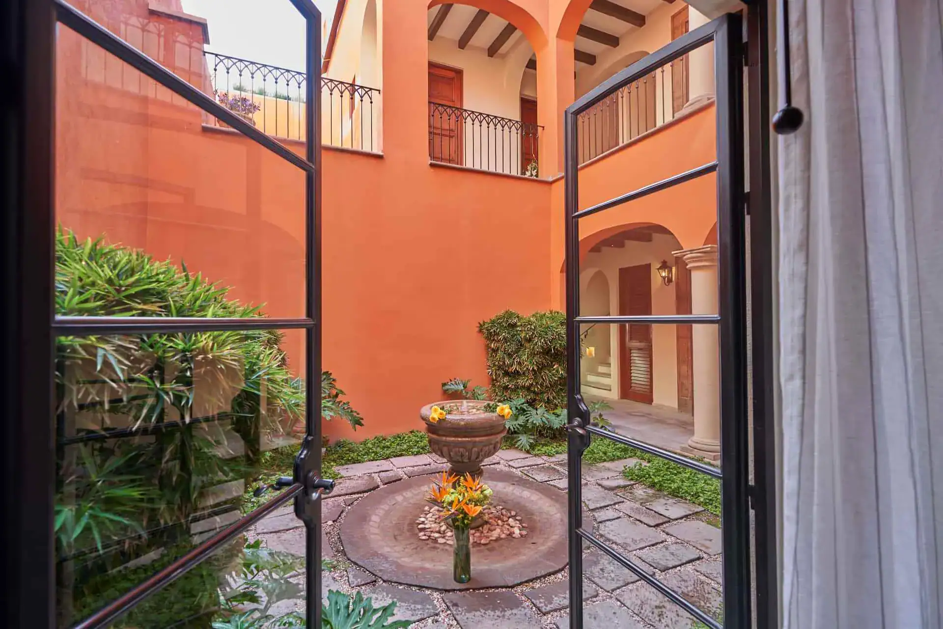 Rosewood Residence 7, courtyard fountain seen through open black steel doors, San Miguel de Allende