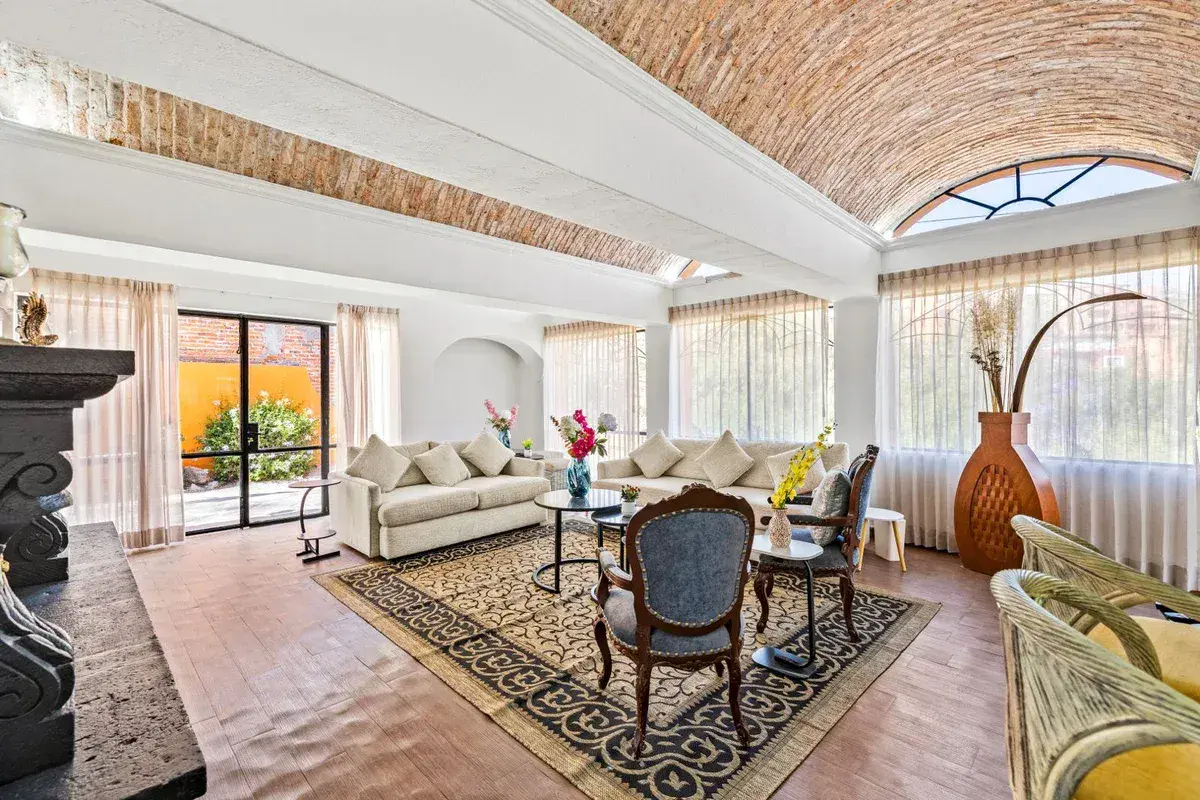 Santo Domingo House, living room with sofas, antique chairs, an area rug and glass doors to the patio, San Miguel de Allende