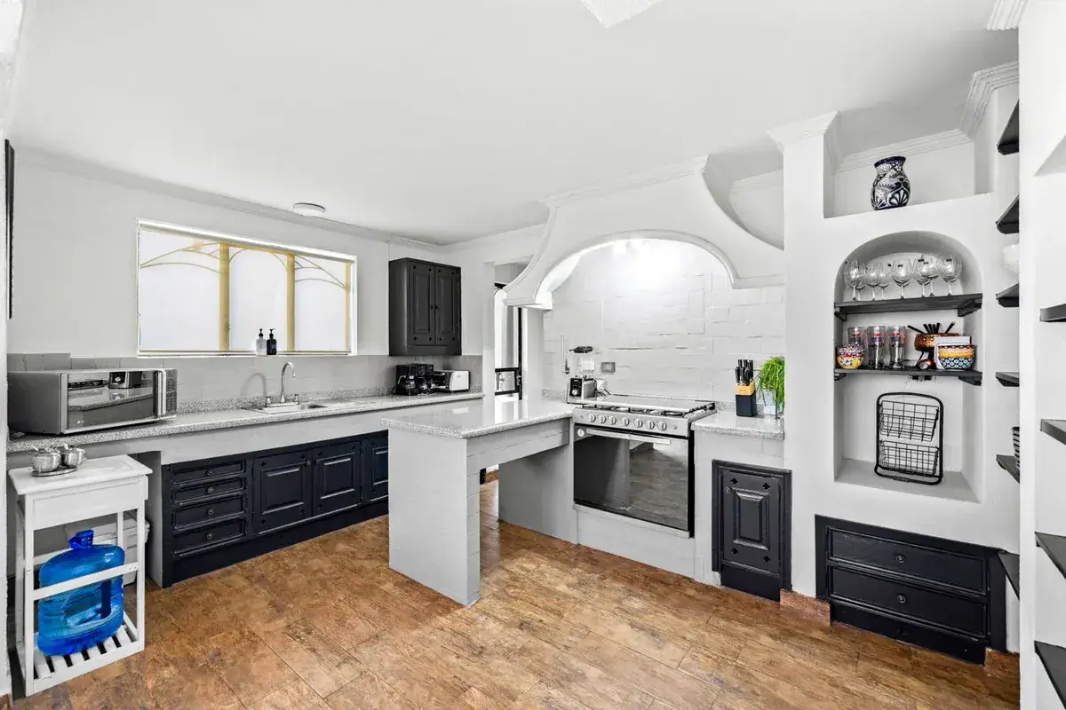 Santo Domingo House, kitchen with navy cabinets, a stainless range, a white counter and a built-in shelf with an arch, San Miguel de Allende