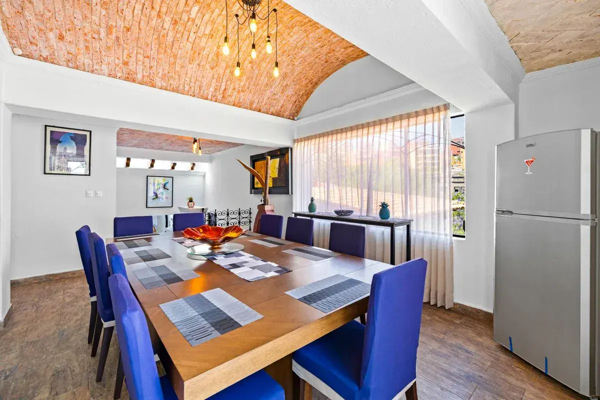 Santo Domingo House, dining room with a long wood table, blue upholstered chairs and a brick vaulted ceiling, San Miguel de Allende