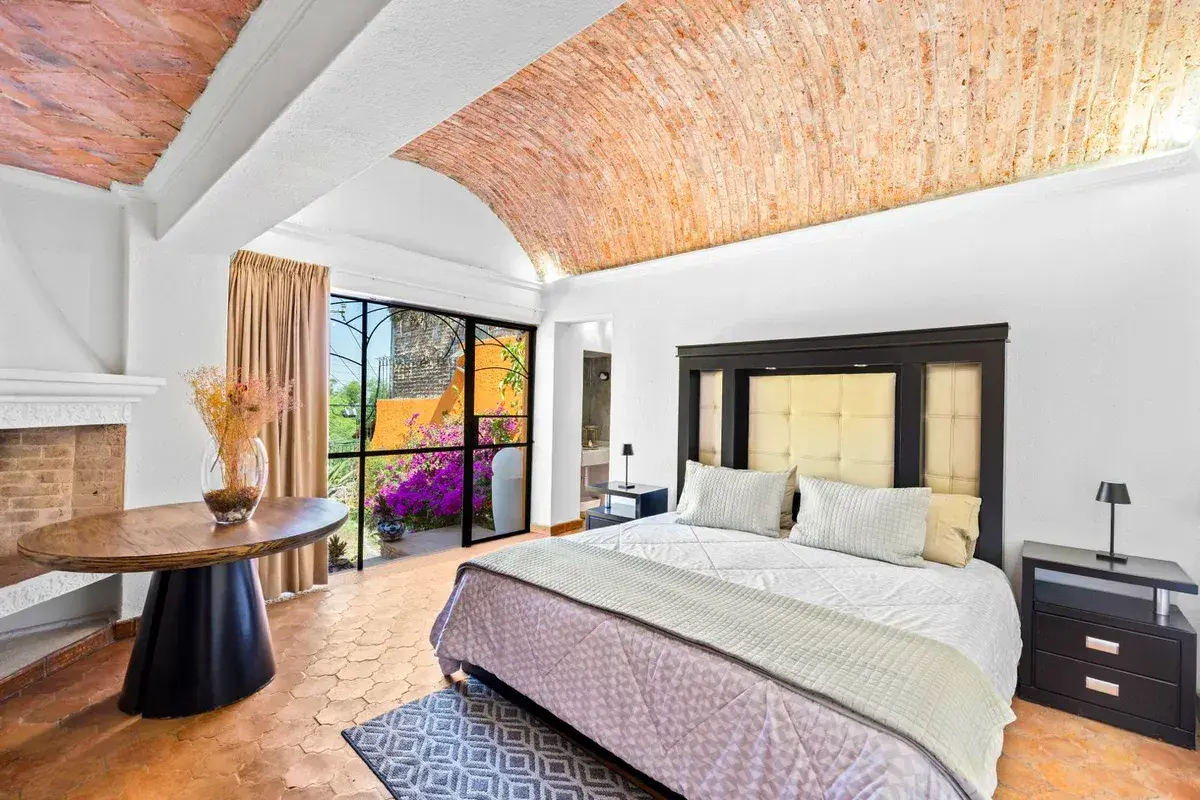 Santo Domingo House, bedroom with a brick vaulted ceiling, a tufted headboard, a round table and a fireplace, San Miguel de Allende