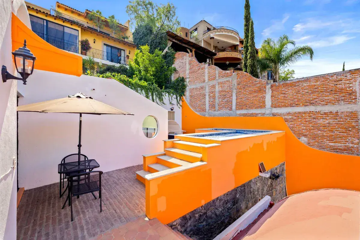 Santo Domingo House, sunken patio with a bistro table, an umbrella, orange steps, a plunge pool and a round window, San Miguel de Allende
