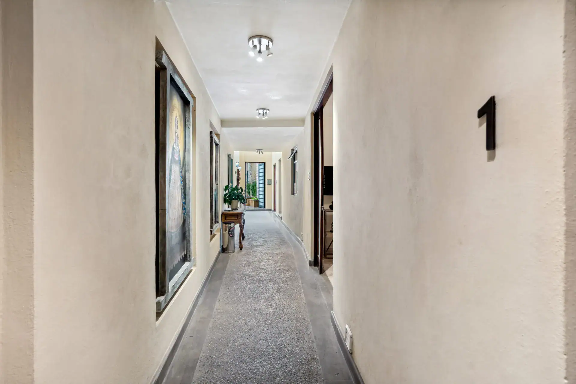 Suites Casa Vistas, long hallway of the suites with a framed painting and the number 1 on the wall, San Miguel de Allende