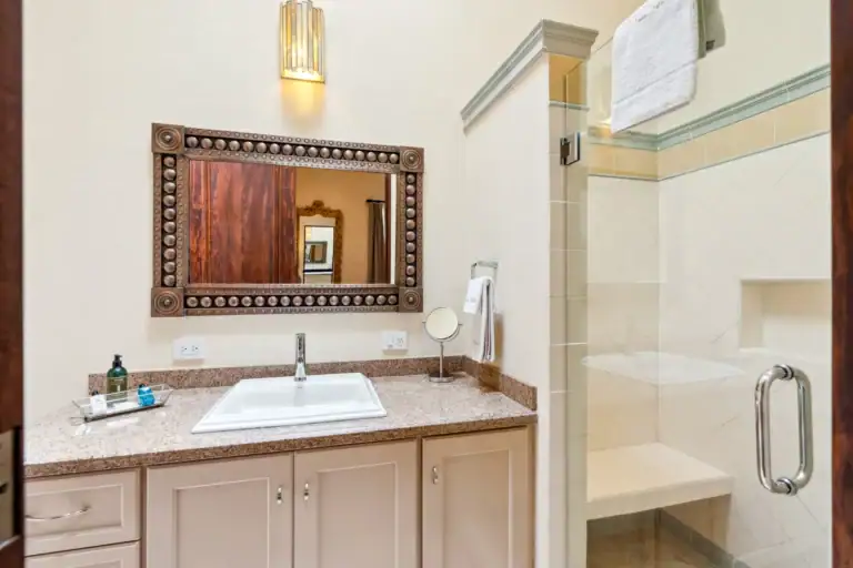 Suites Casa Vistas, bathroom with a beige vanity, studded wood-framed mirror and a glass shower, San Miguel de Allende