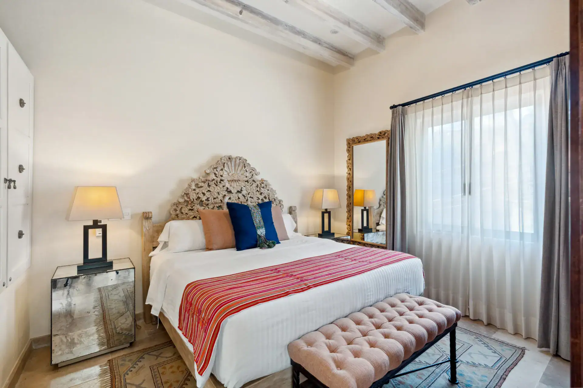 Suites Casa Vistas, bedroom with a carved headboard, pink striped runner and sheer curtains, San Miguel de Allende