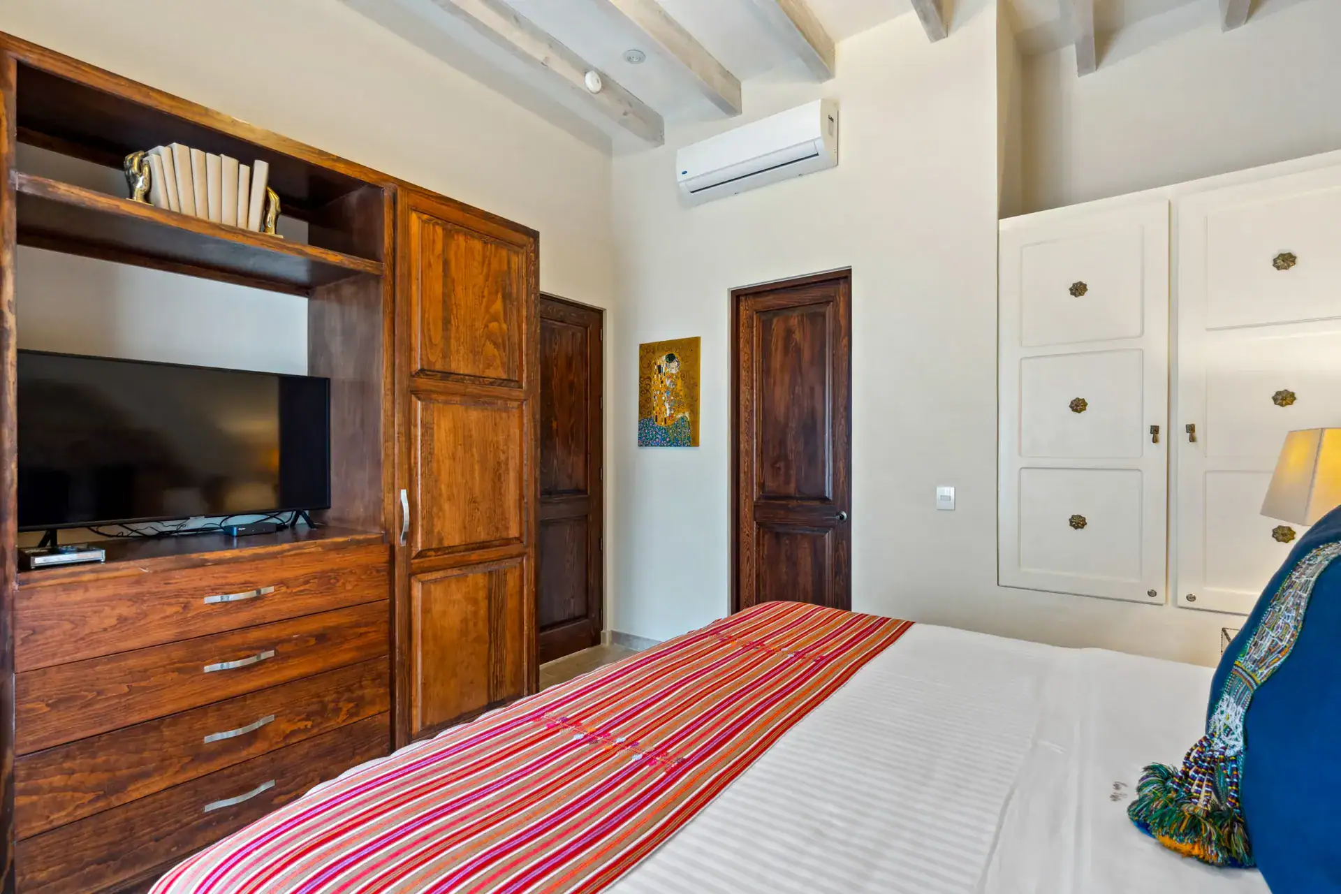 Suites Casa Vistas, bedroom with a built-in wood television cabinet and a striped bed runner, San Miguel de Allende