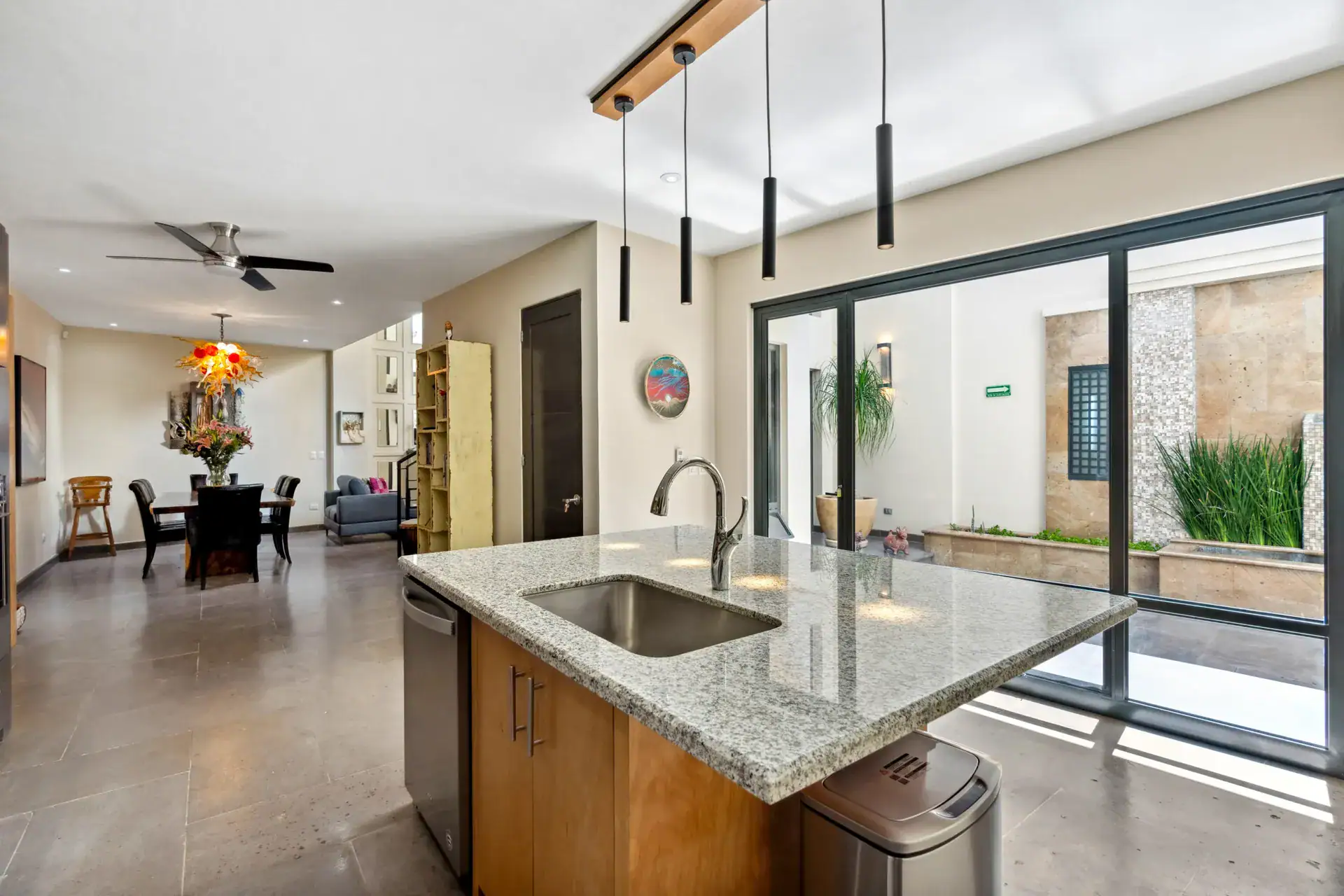 Suites Casa Vistas, kitchen island and dining area beside floor-to-ceiling glass doors to a courtyard, San Miguel de Allende