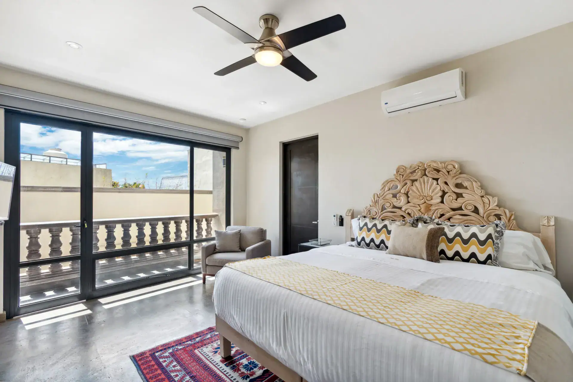 Suites Casa Vistas, bedroom with a carved headboard and sliding glass doors to a balcony, San Miguel de Allende