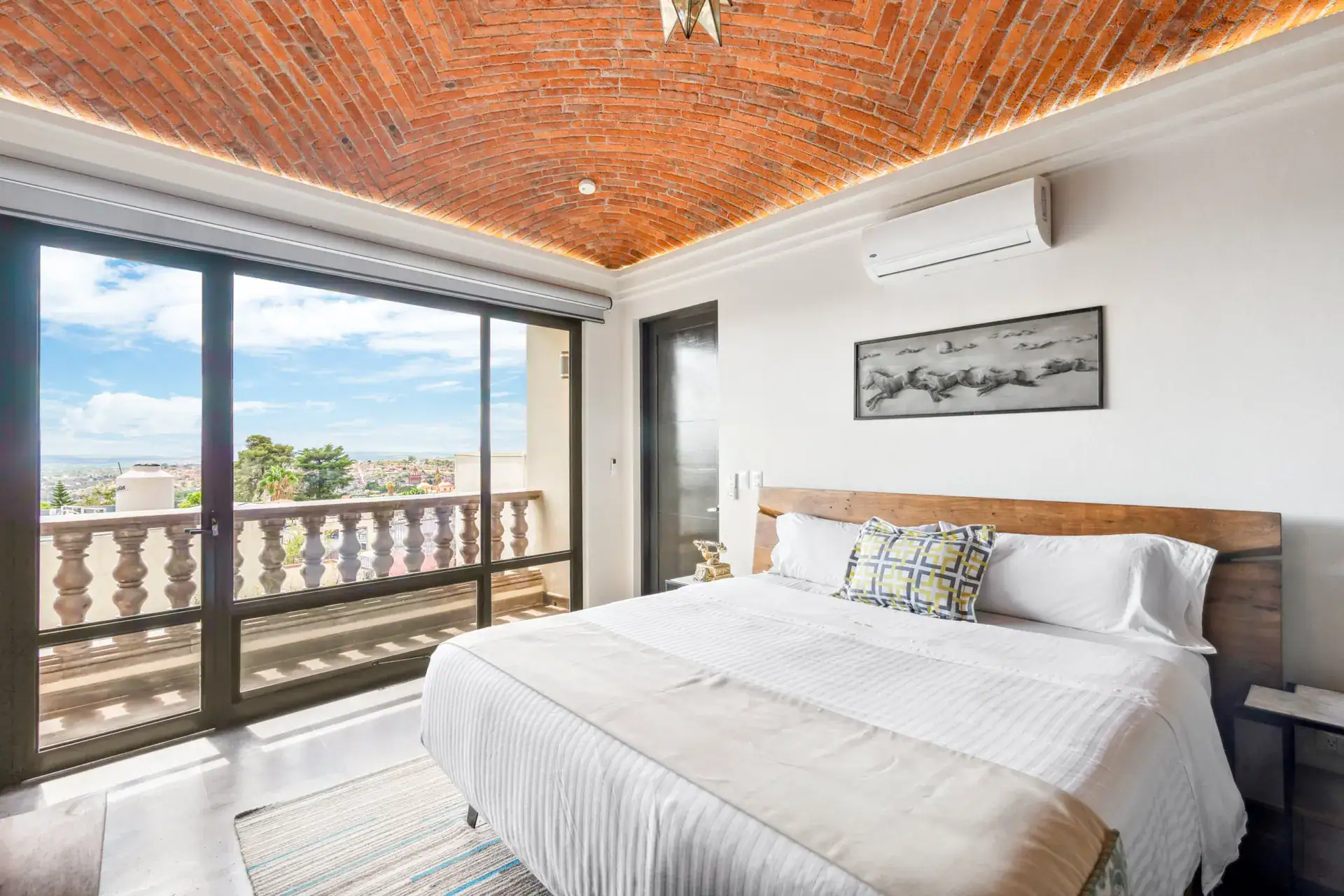 Suites Casa Vistas, bedroom with a wood headboard, balcony doors and a brick vaulted ceiling, San Miguel de Allende