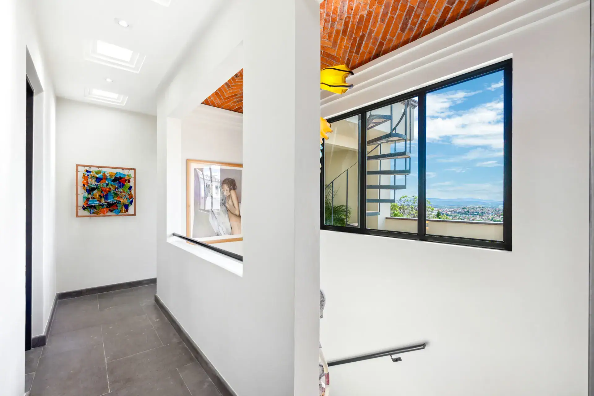 Suites Casa Vistas, landing with colorful artwork, a spiral staircase and a window onto the sky, San Miguel de Allende