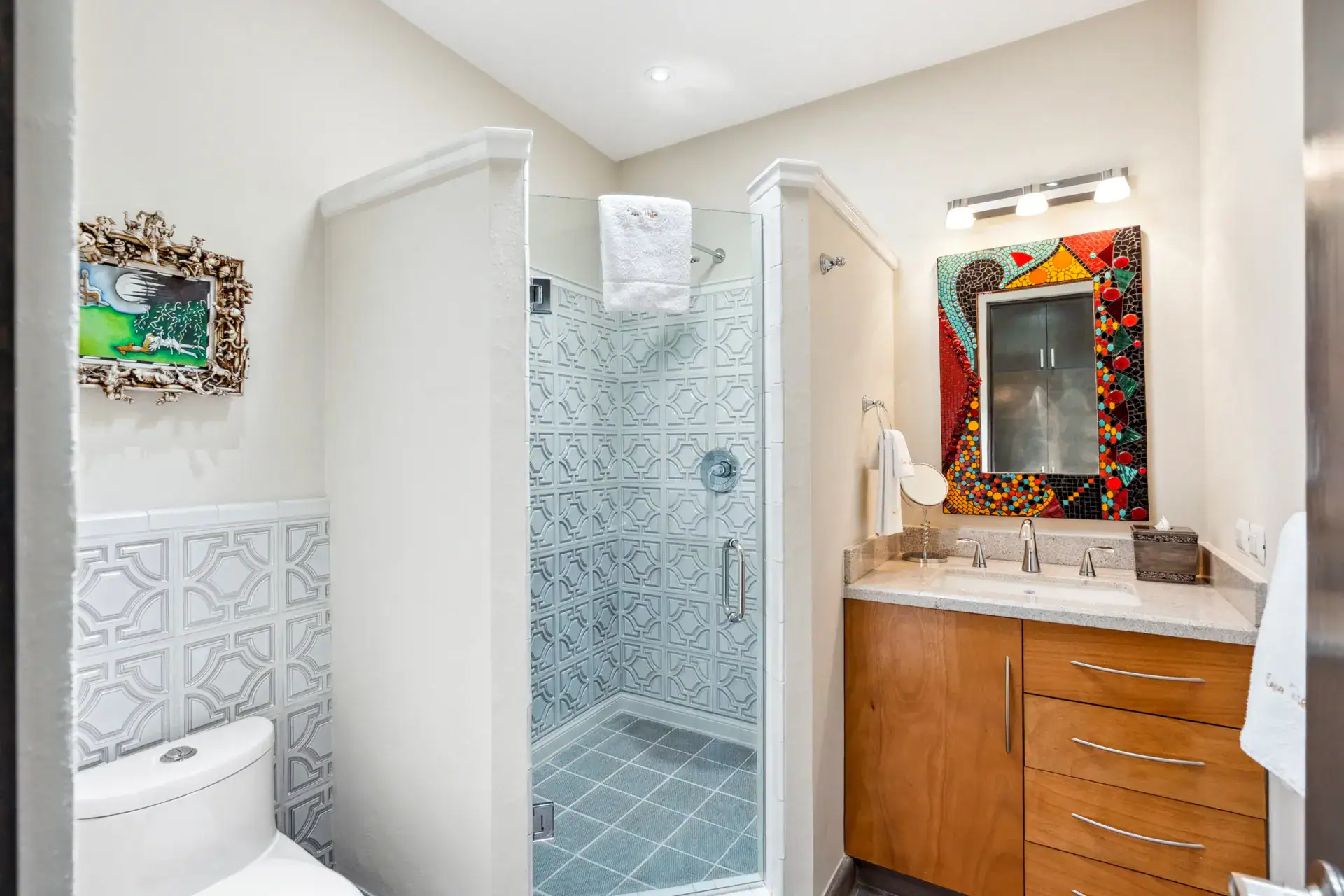 Suites Casa Vistas, bathroom with a patterned tile shower, wood vanity and a mosaic mirror, San Miguel de Allende