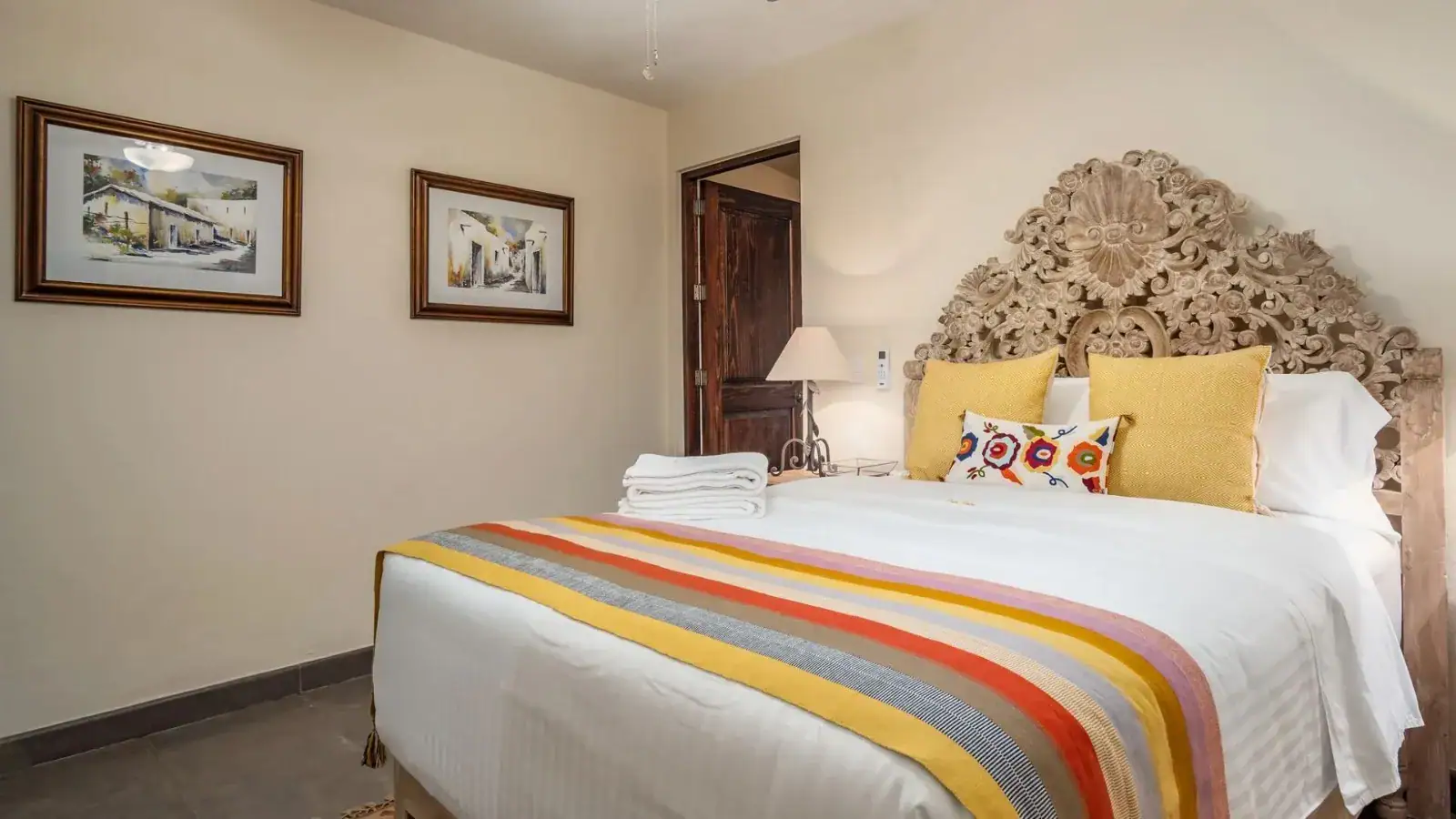 Suites Casa Vistas, bedroom with a carved headboard, yellow pillows and a striped bed runner, San Miguel de Allende