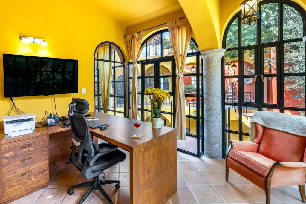 Home office with a wood desk, ergonomic chair and arched black-framed windows, San Miguel de Allende