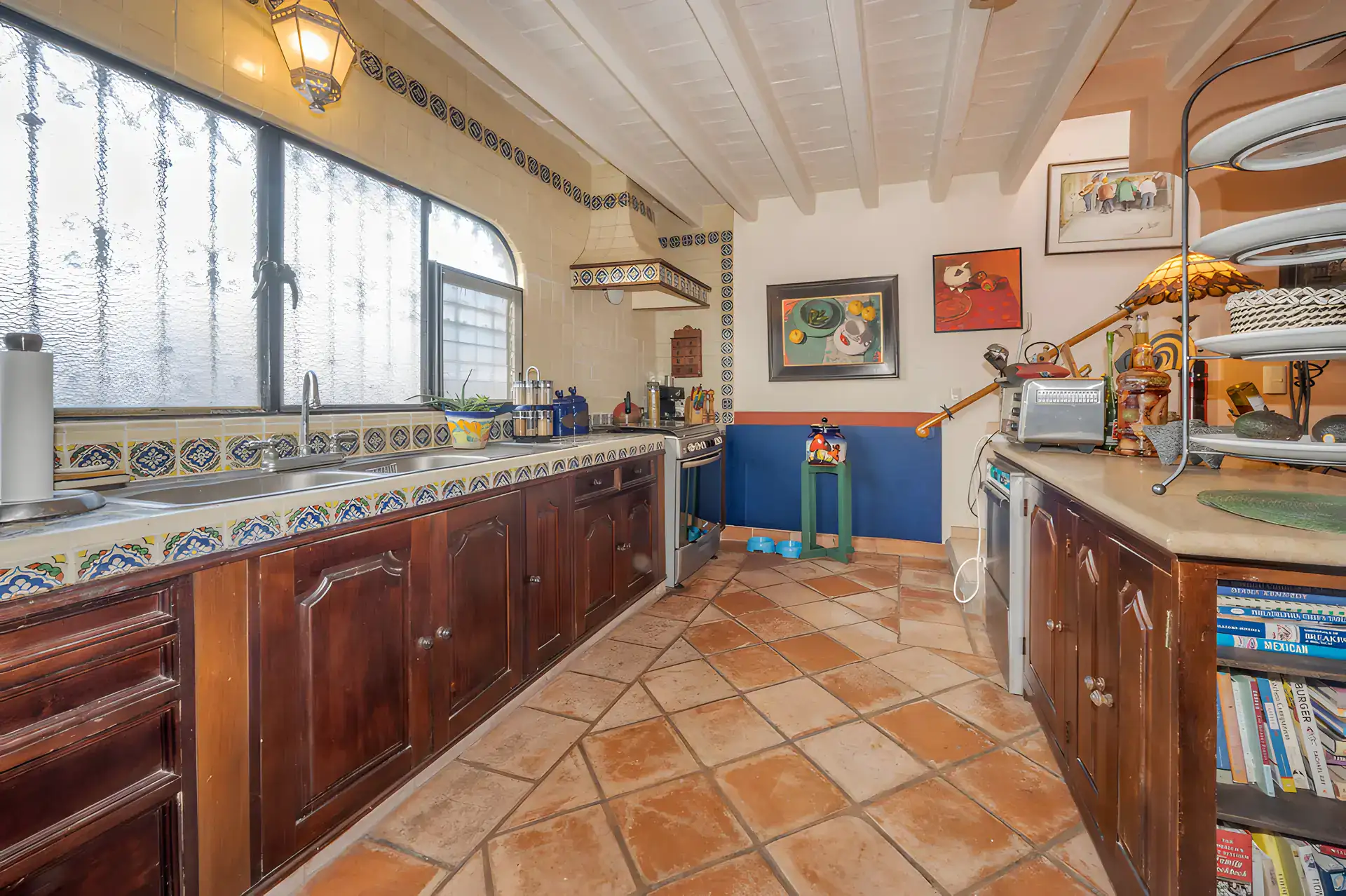 Two Homes, tile kitchen with dark wood cabinets, a long countertop with Talavera tile border and a tile floor, San Miguel de Allende