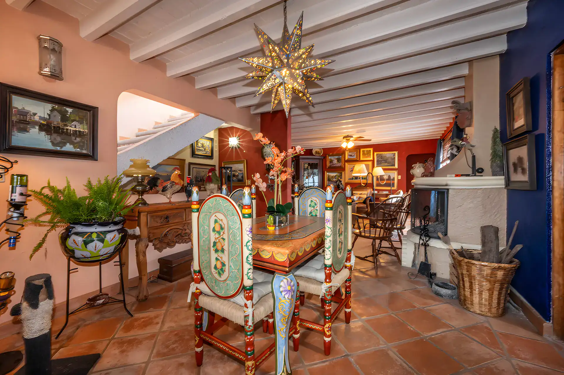 Two Homes, dining room with a painted wood table and chairs, a tin star lantern and a living room beyond, San Miguel de Allende