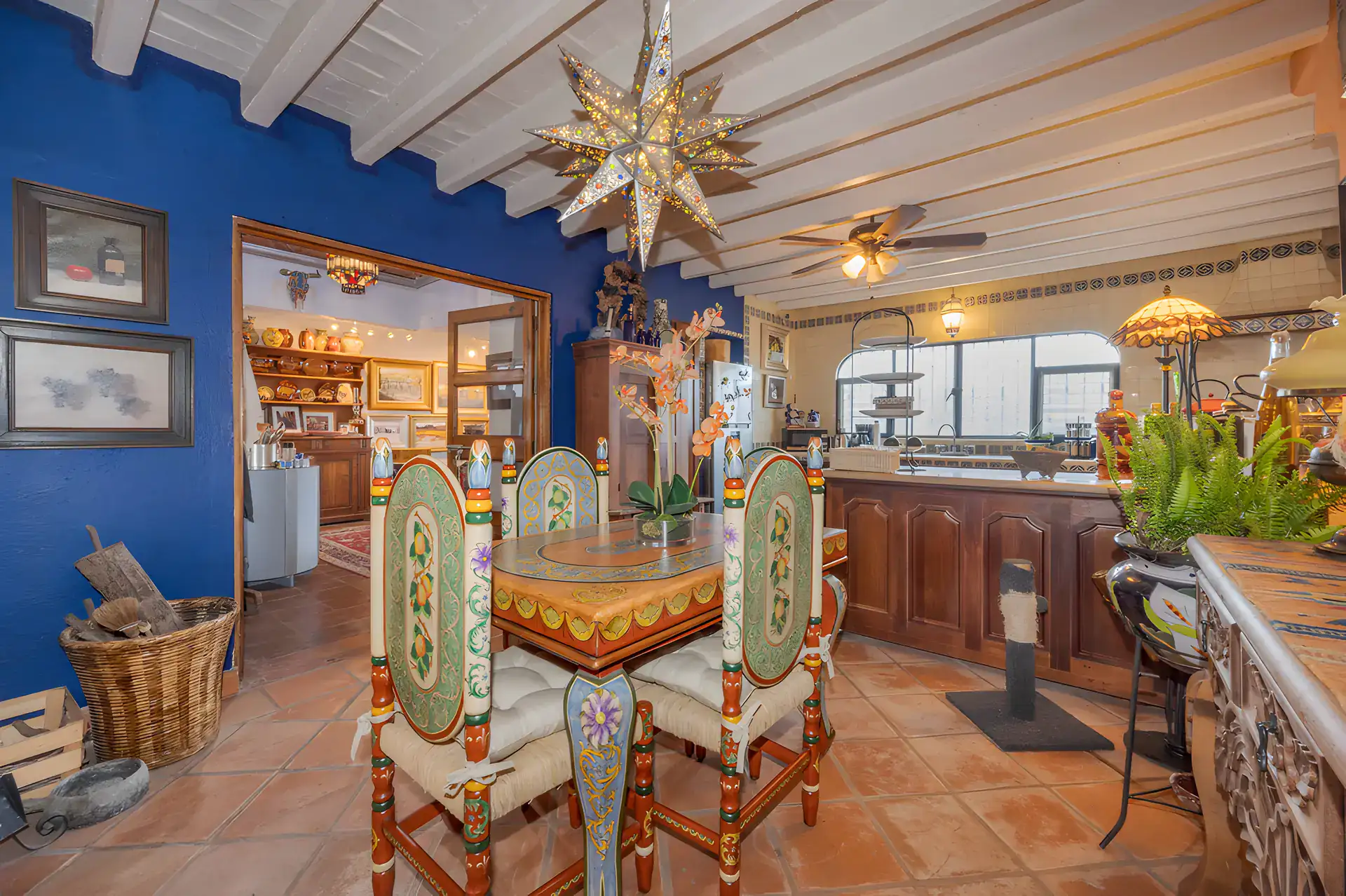 Two Homes, dining area and kitchen with a blue wall, a hanging tin star and an arched passage, San Miguel de Allende