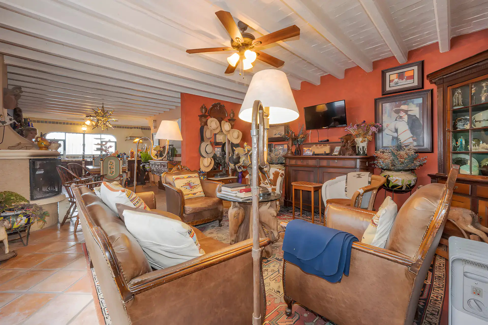 Two Homes, living room with leather armchairs, a stone fireplace and a collection of hats and paintings, San Miguel de Allende