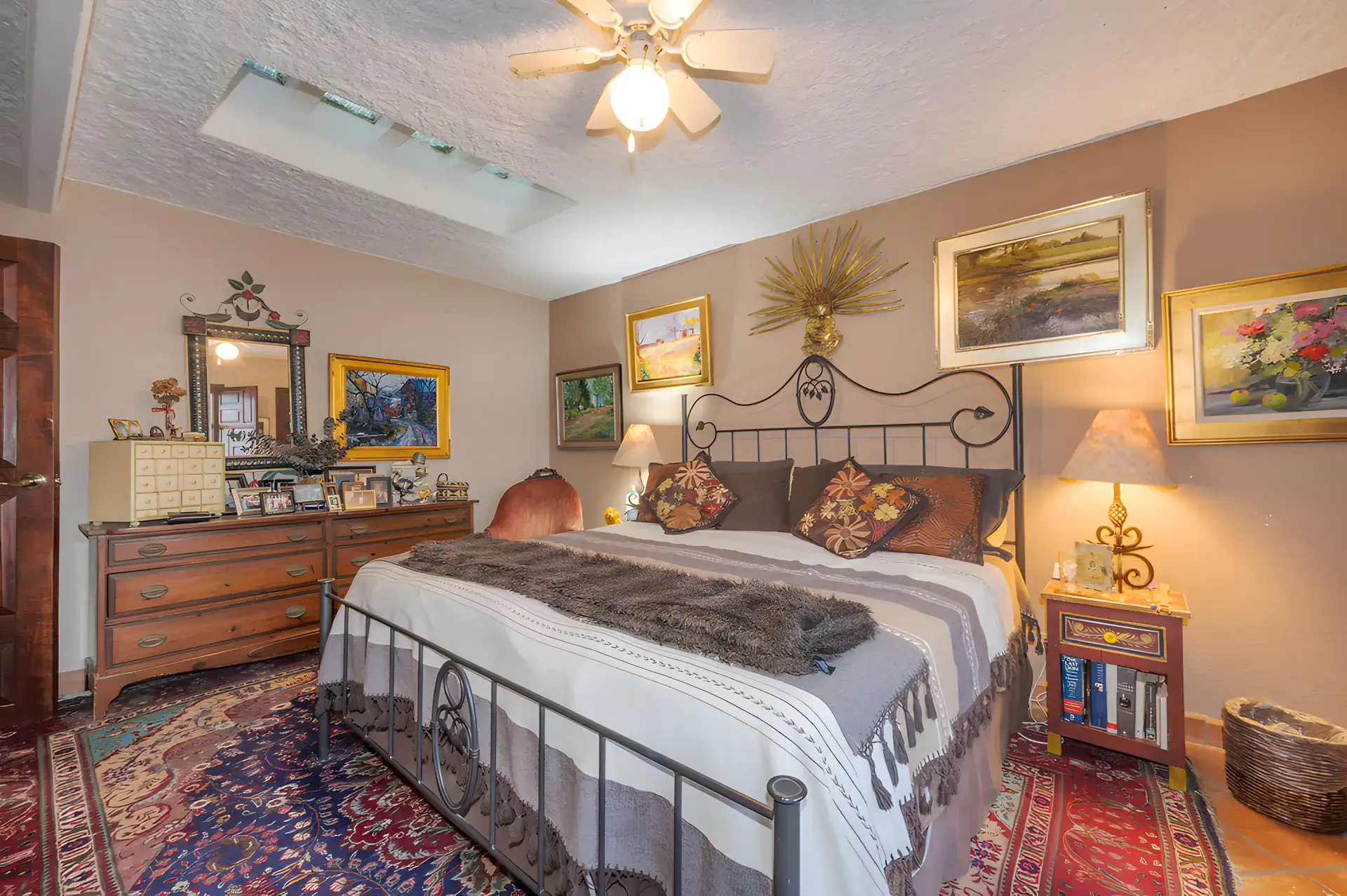 Two Homes, bedroom with a wrought-iron bed, a wood dresser, Persian rugs and a skylight, San Miguel de Allende