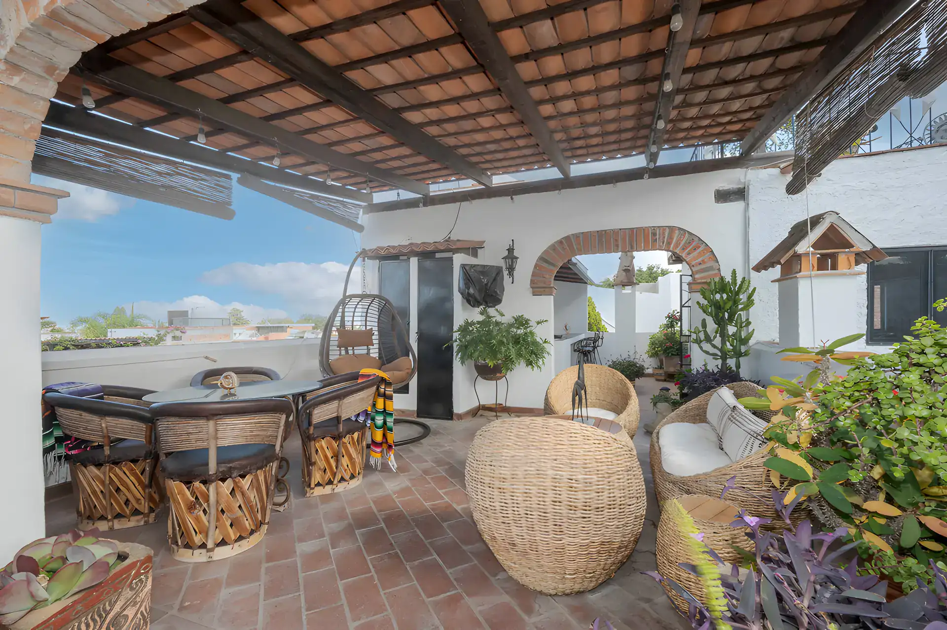 Two Homes, covered rooftop pavilion with a round table, equipale chairs and wicker seating, San Miguel de Allende