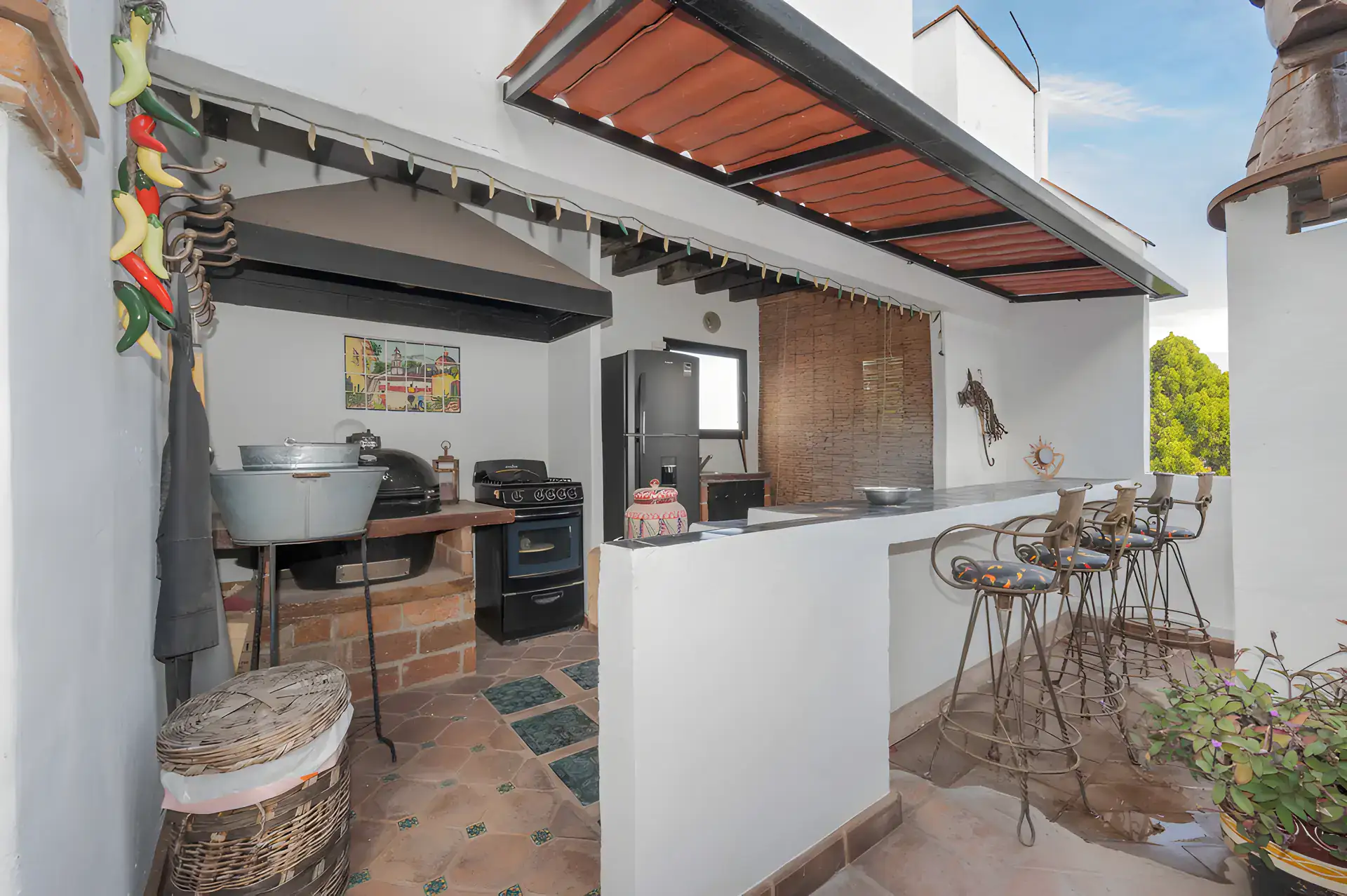 Two Homes, outdoor kitchen on the roof with a wood-fired oven, a grill and a bar with stools, San Miguel de Allende