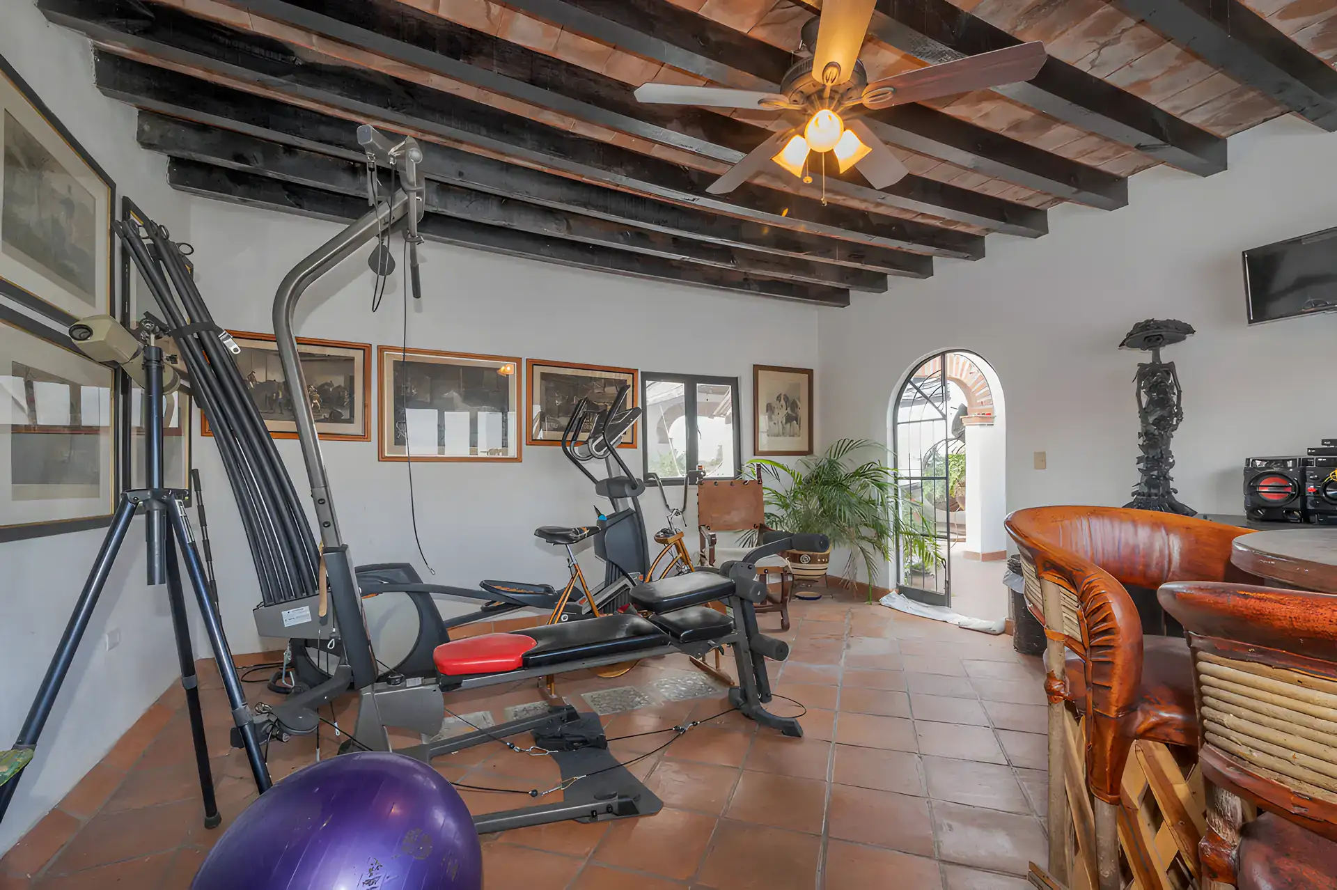 Two Homes, rooftop game and exercise room with a gym machine, a treadmill, leather chairs and a wood beam ceiling, San Miguel de Allende