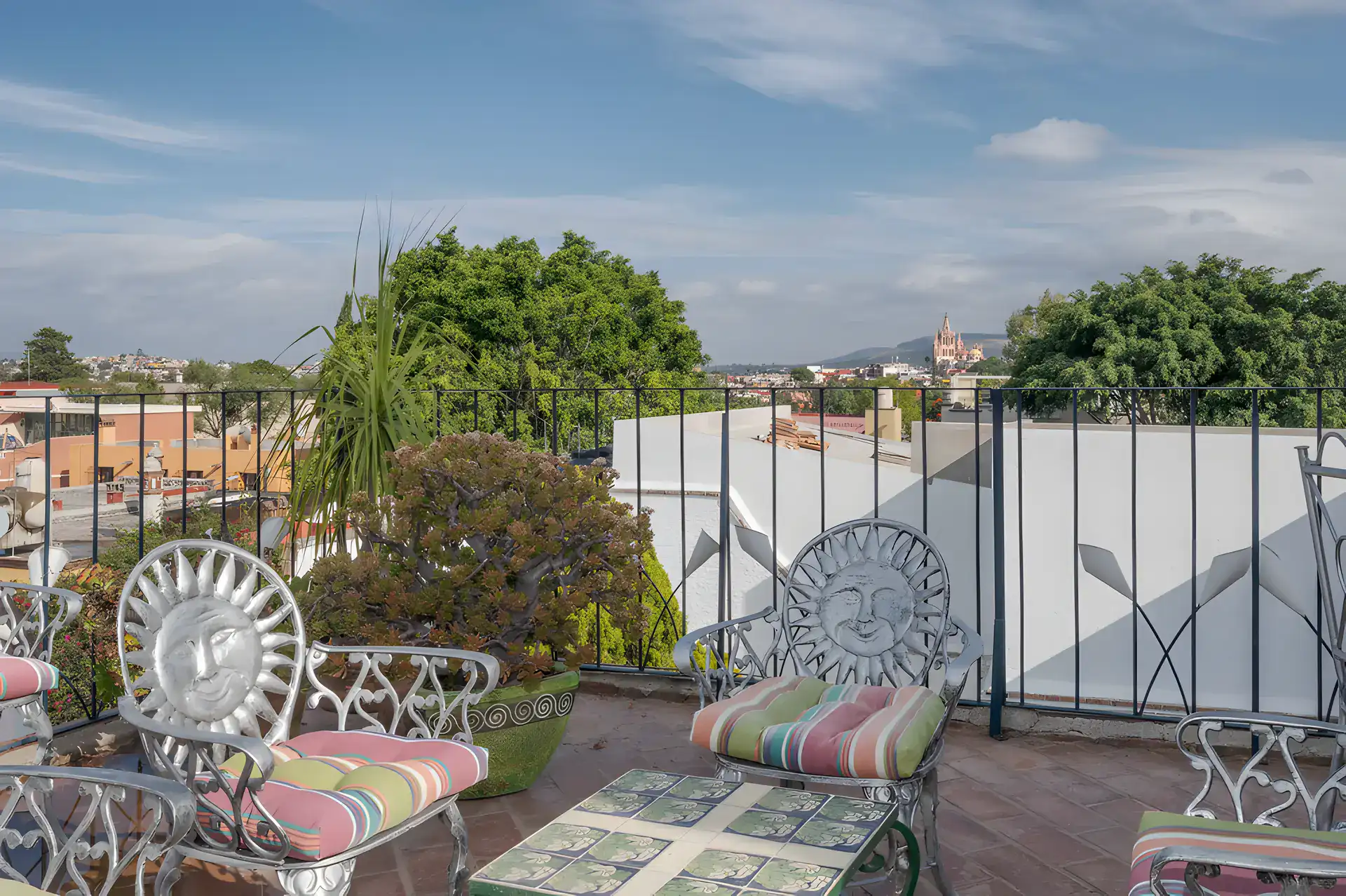 Two Homes, rooftop seating with sun-face metal chairs and a view of the Parroquia and hills, San Miguel de Allende
