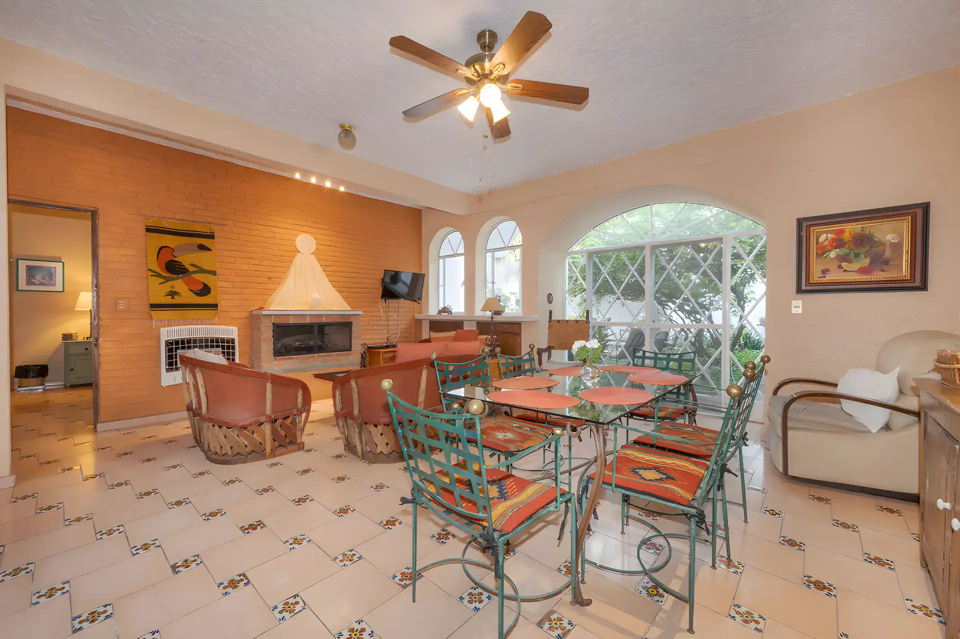 Two Homes, guest apartment living room with a brick wall, a fireplace and a green wrought iron dining set, San Miguel de Allende