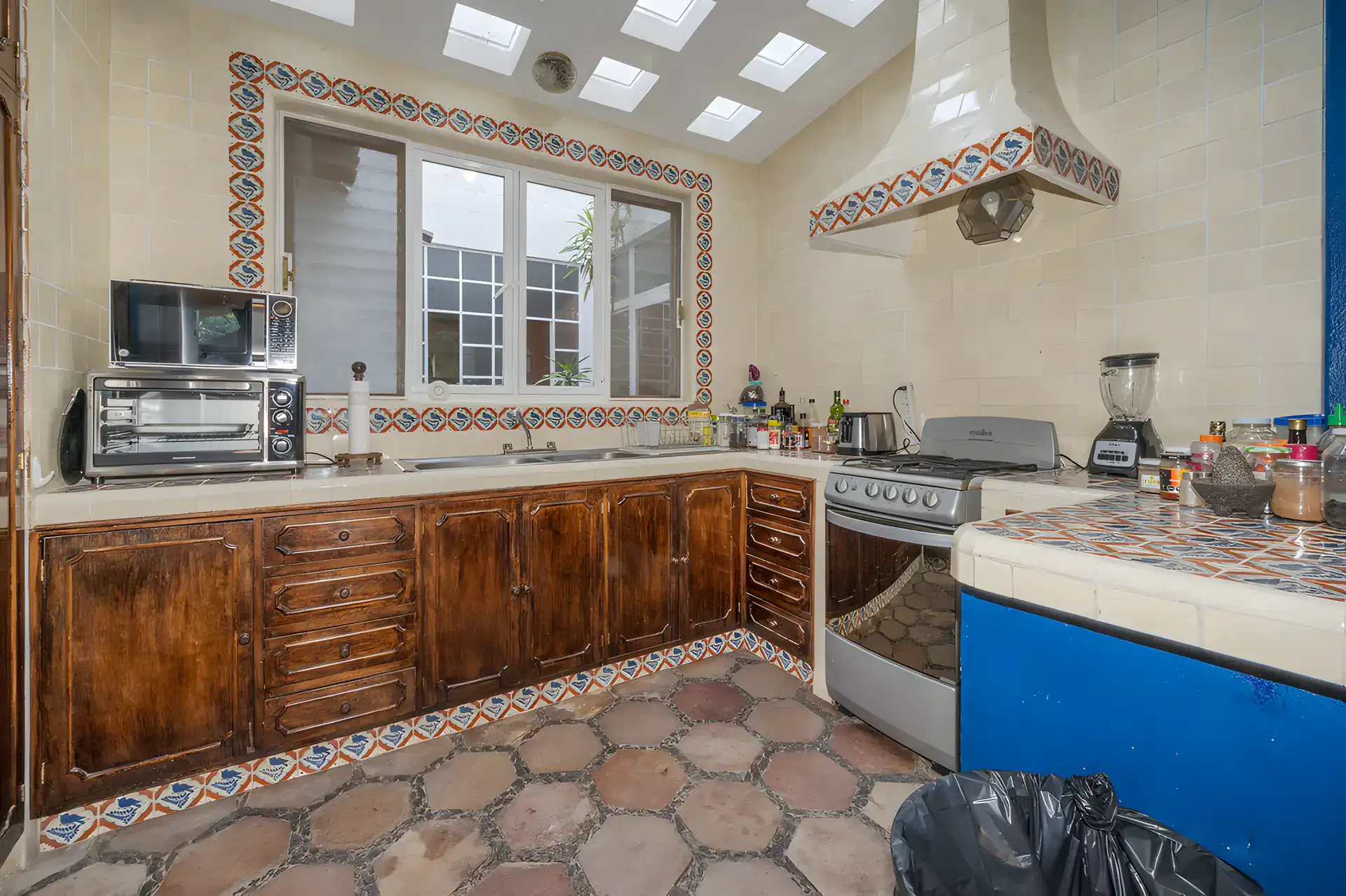 Two Homes, guest apartment kitchen with dark wood cabinets, a gas range, a tile hood and skylights, San Miguel de Allende