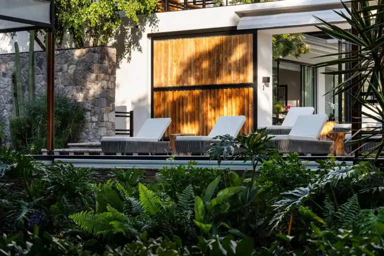 Villa del Parque Central, white contemporary villa with a wood-slat screen and lounge chairs above lush ferns and garden, San Miguel de Allende
