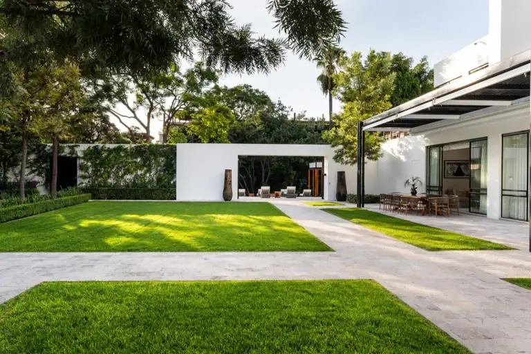 Villa del Parque Central, travertine paths and lawn leading to a covered dining terrace and a white garden pavilion, San Miguel de Allende