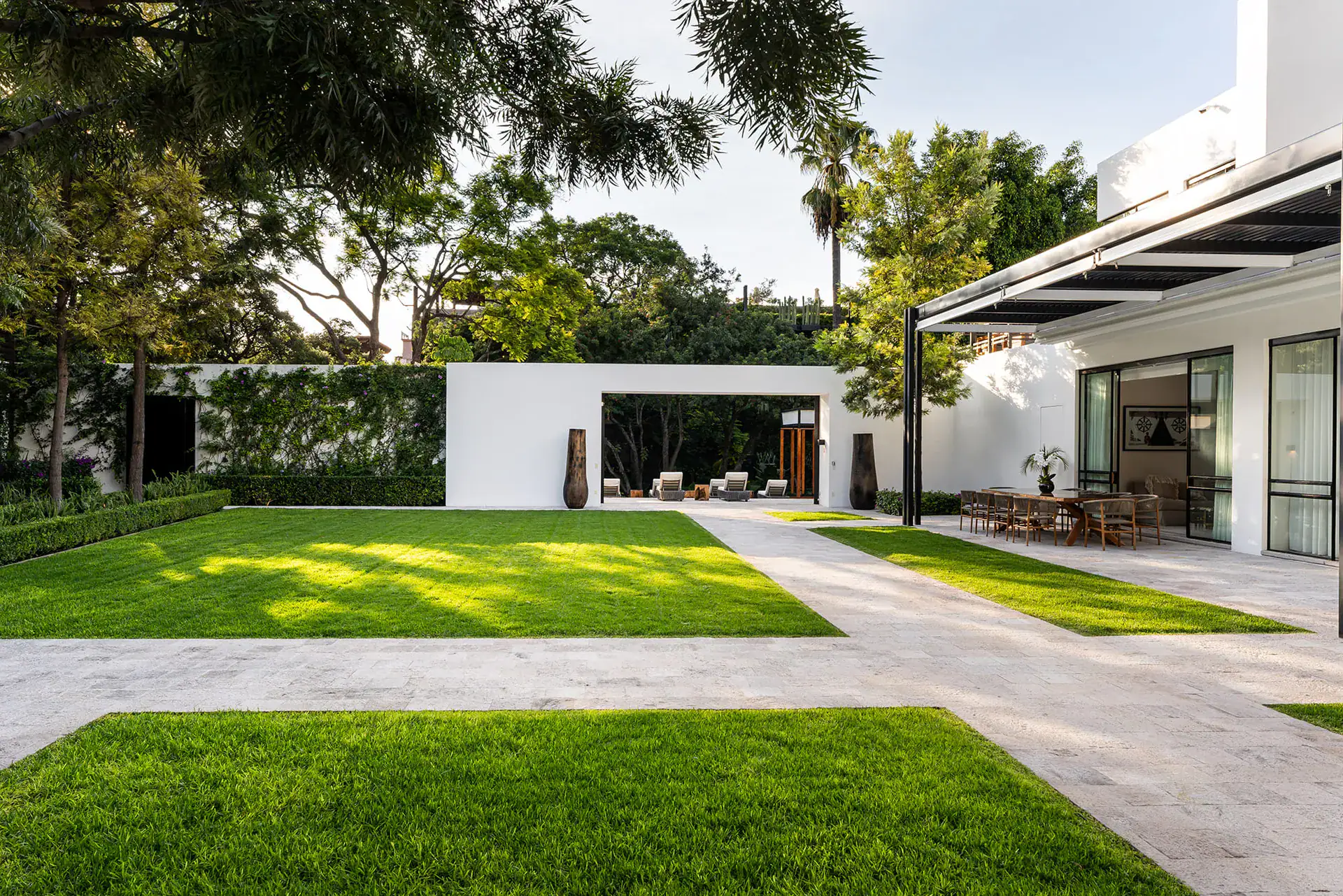 Villa del Parque Central, travertine paths and lawn leading to a covered dining terrace and a white garden pavilion, San Miguel de Allende
