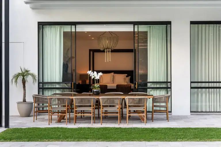 Villa del Parque Central, outdoor dining table for ten in front of a glass-walled bedroom with a hanging light, San Miguel de Allende
