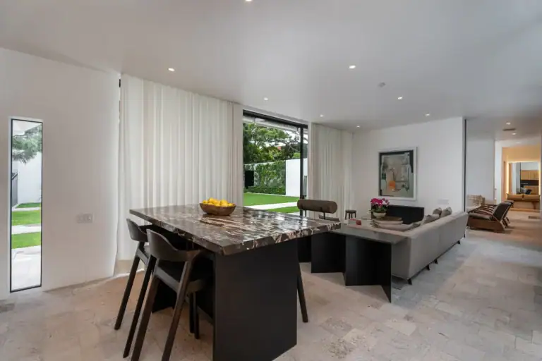 Villa del Parque Central, living and dining area with a stone-topped table, gray sofa and sliding glass walls opening to the lawn, San Miguel de Allende