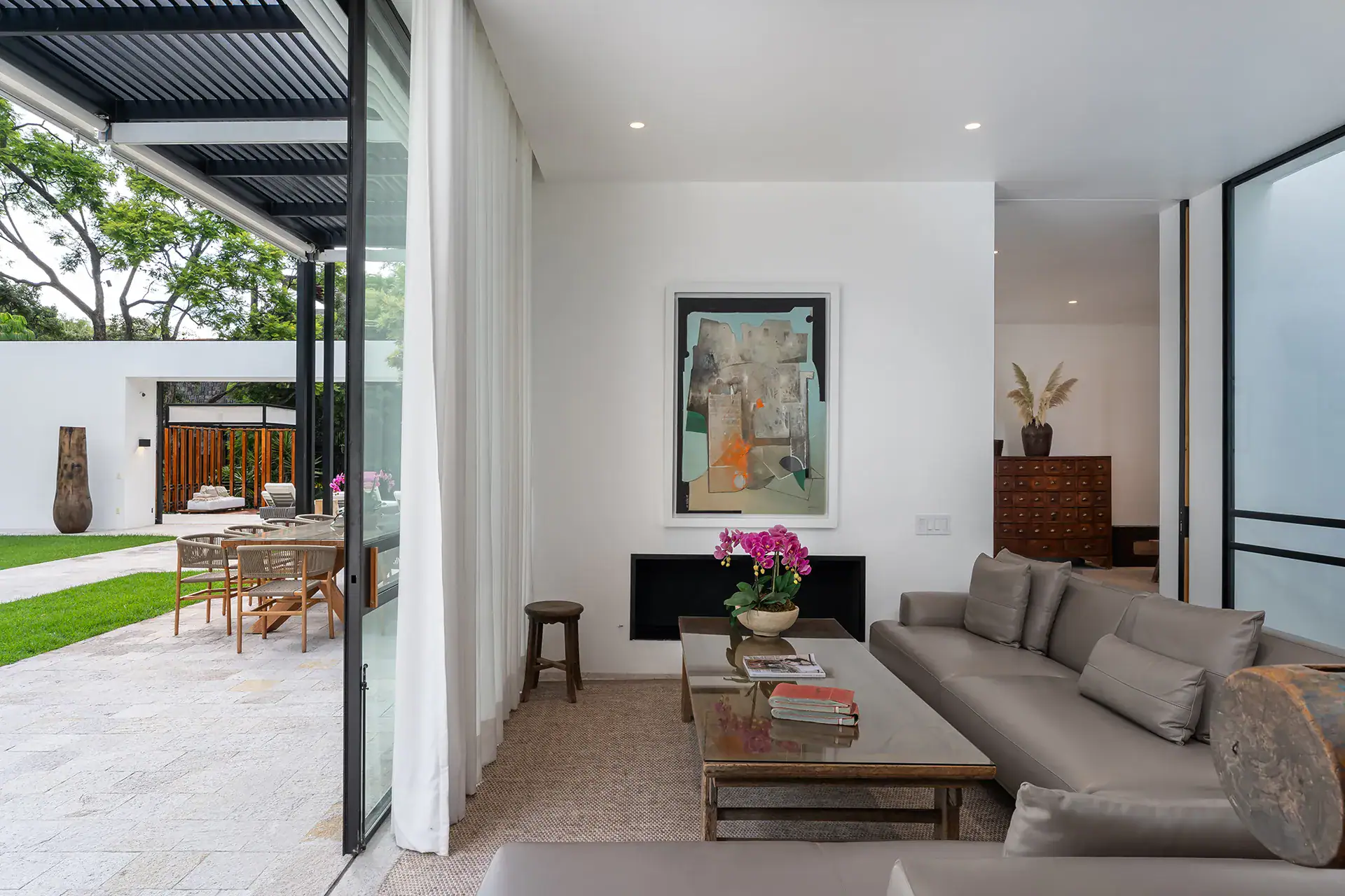 Villa del Parque Central, living room with a gray sofa and artwork opening onto the garden terrace, San Miguel de Allende