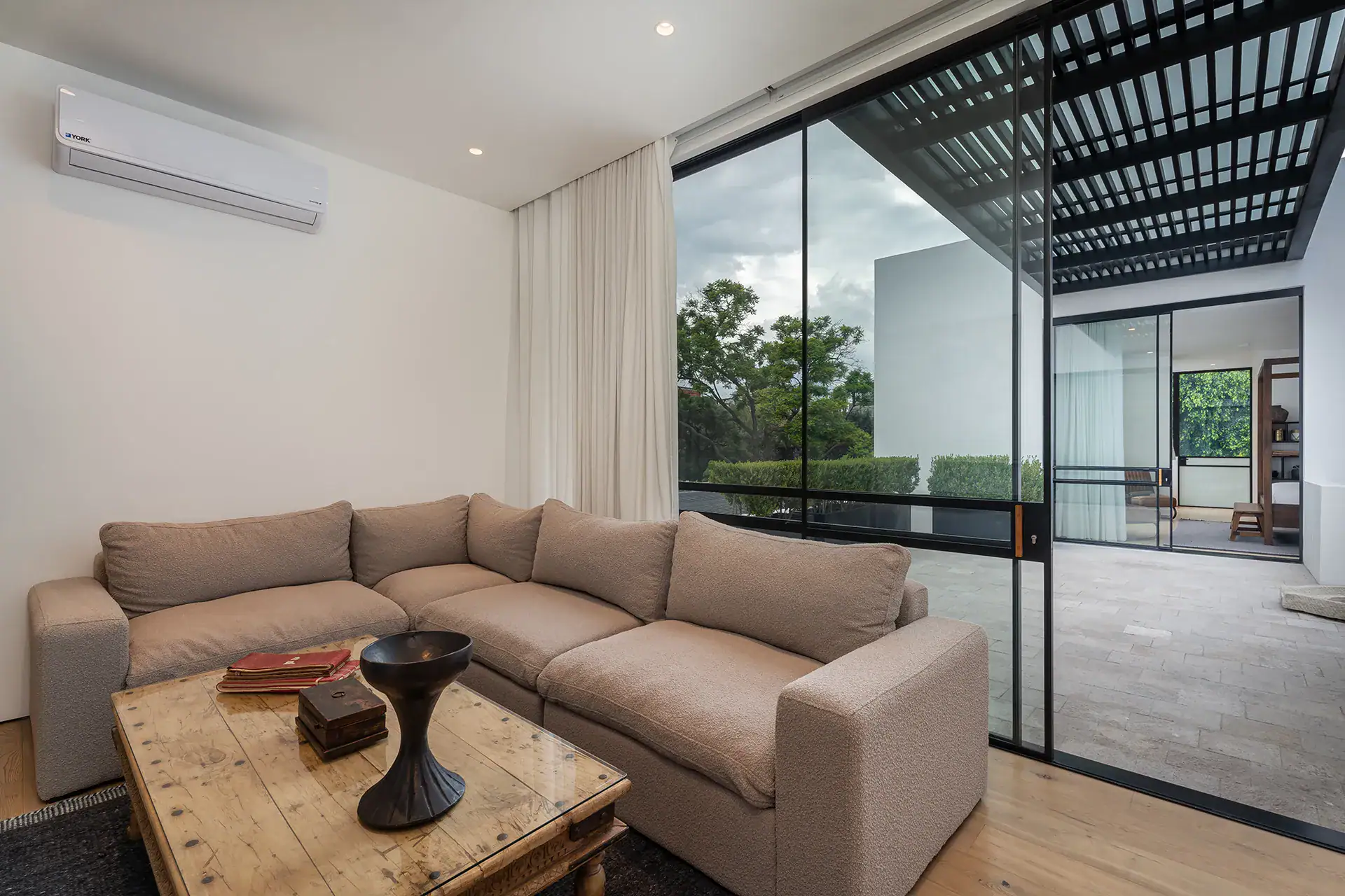 Villa del Parque Central, small lounge with a beige sectional, wood coffee table and sliding glass doors to a terrace, San Miguel de Allende