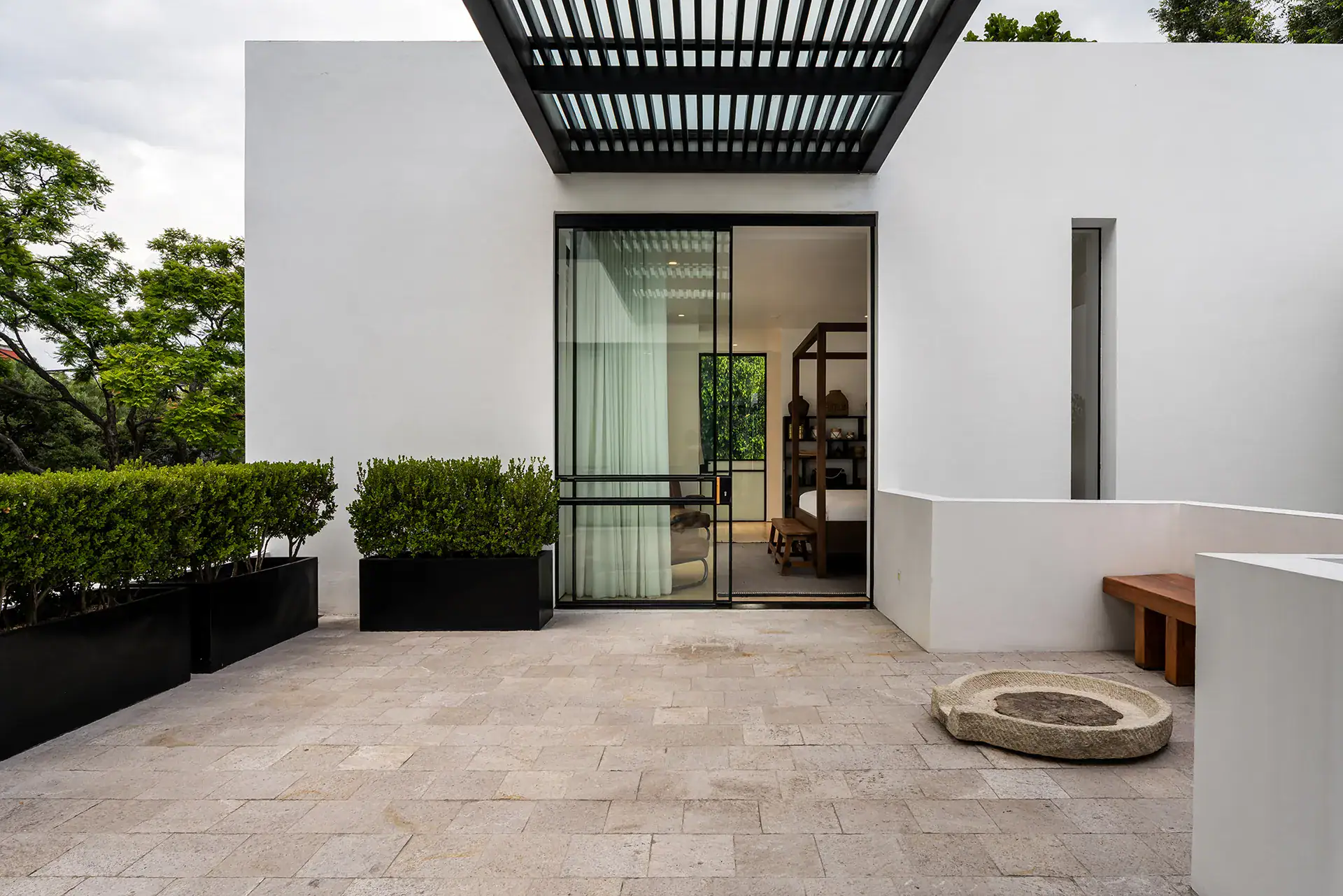 Villa del Parque Central, private terrace with trimmed hedges, stone paving and a glass door to a bedroom, San Miguel de Allende