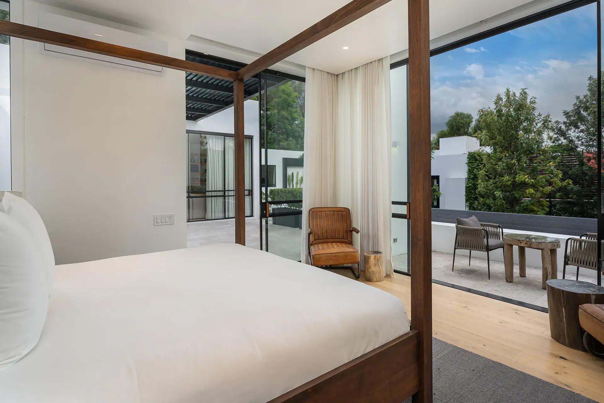 Villa del Parque Central, four-poster bed with glass doors opening onto a terrace with outdoor seating, San Miguel de Allende