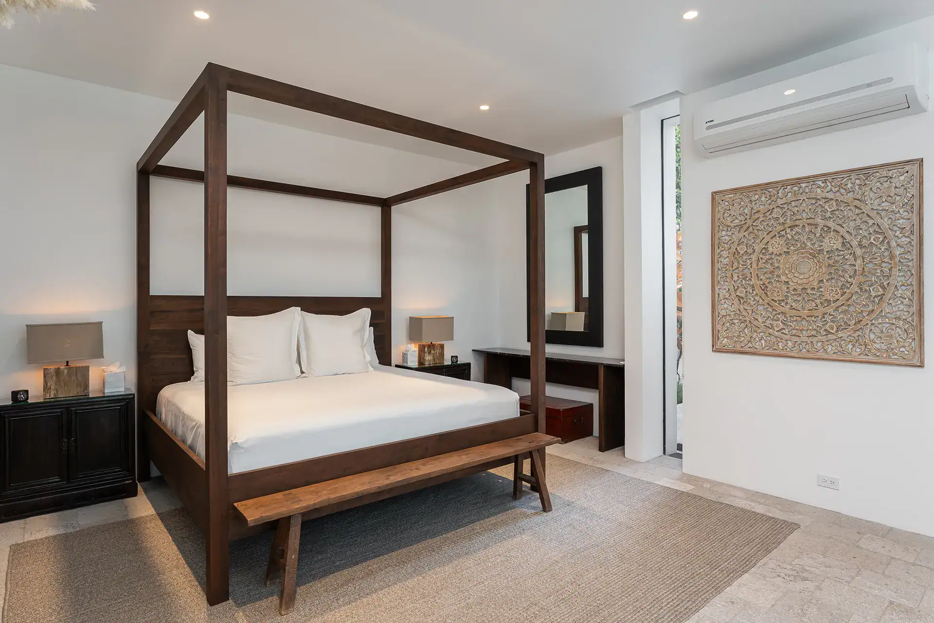 Villa del Parque Central, bedroom with a dark wood four-poster bed, carved wall panel and wall-mounted air conditioner, San Miguel de Allende