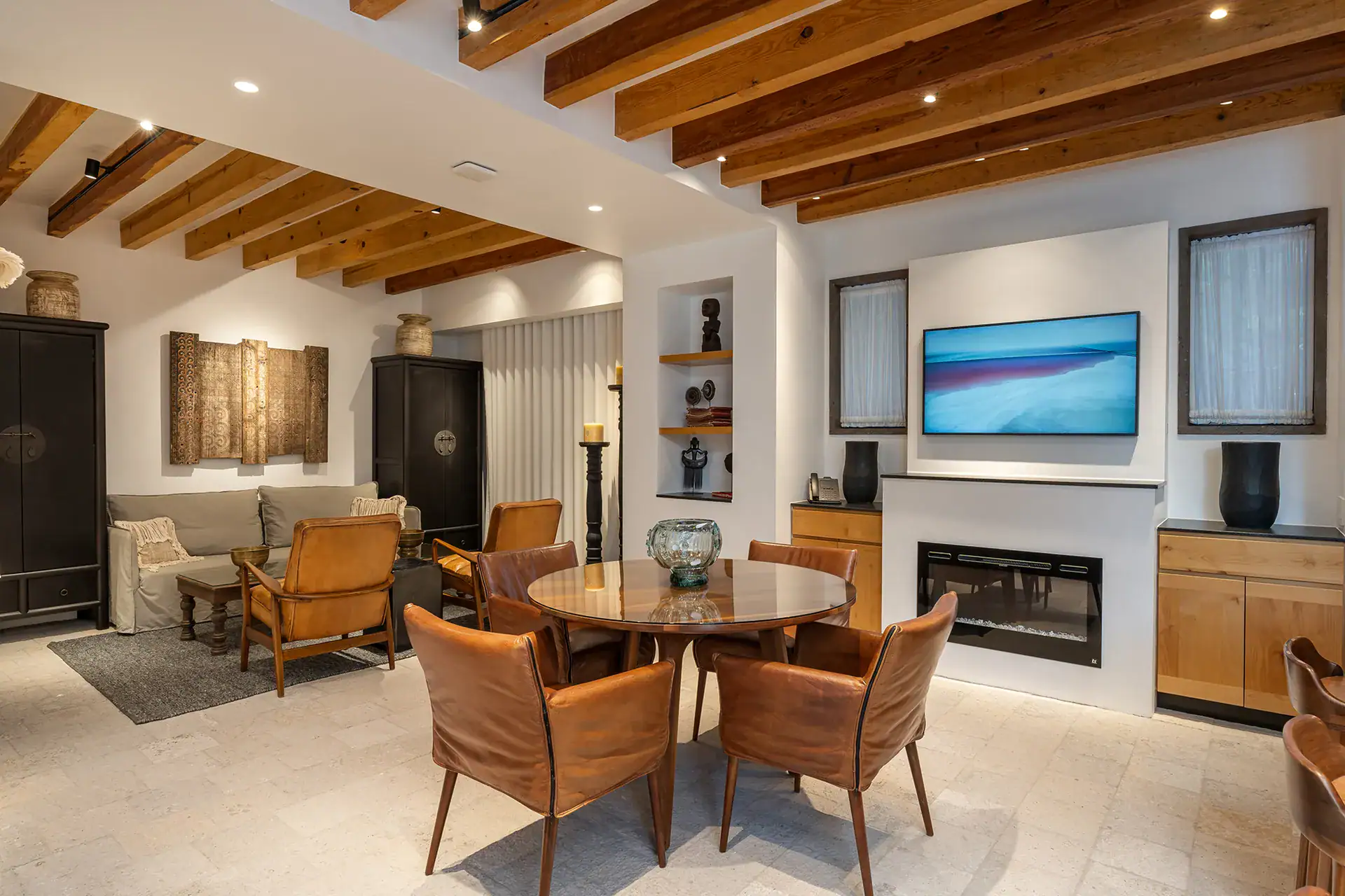 Villa del Parque Central, living and dining area with a round table, leather chairs and a black armoire under exposed beams, San Miguel de Allende