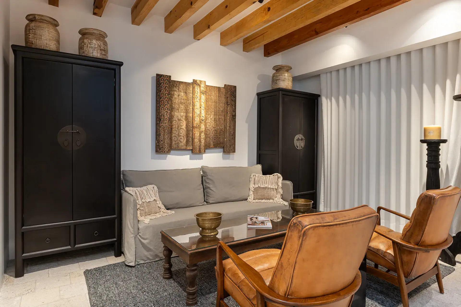 Villa del Parque Central, sitting area with gray sofa, leather armchairs and black armoire beneath a beamed ceiling, San Miguel de Allende