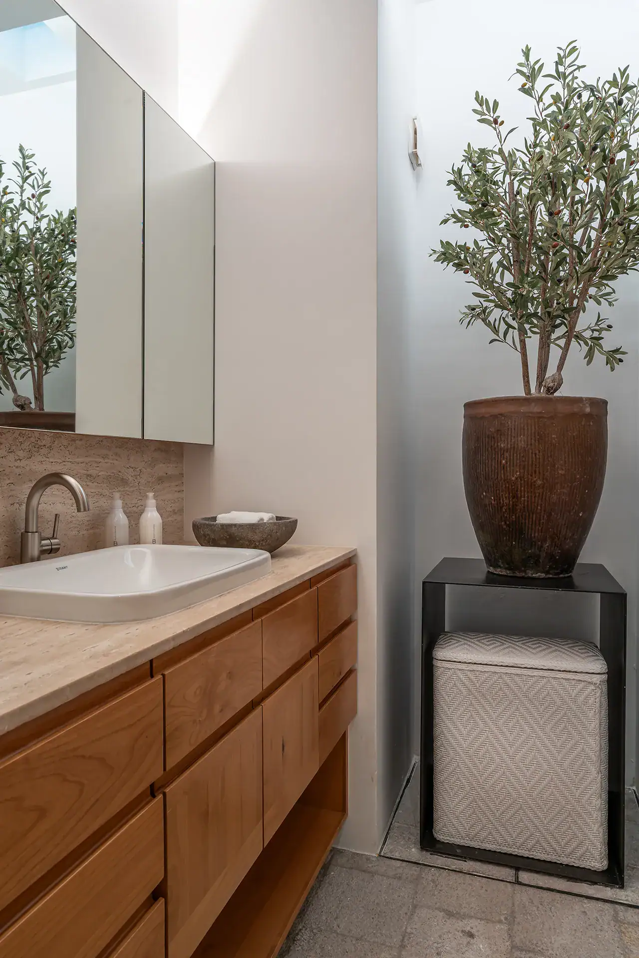 Villa del Parque Central, bathroom with an oak vanity, mirrored cabinet and an olive tree in a skylit nook, San Miguel de Allende