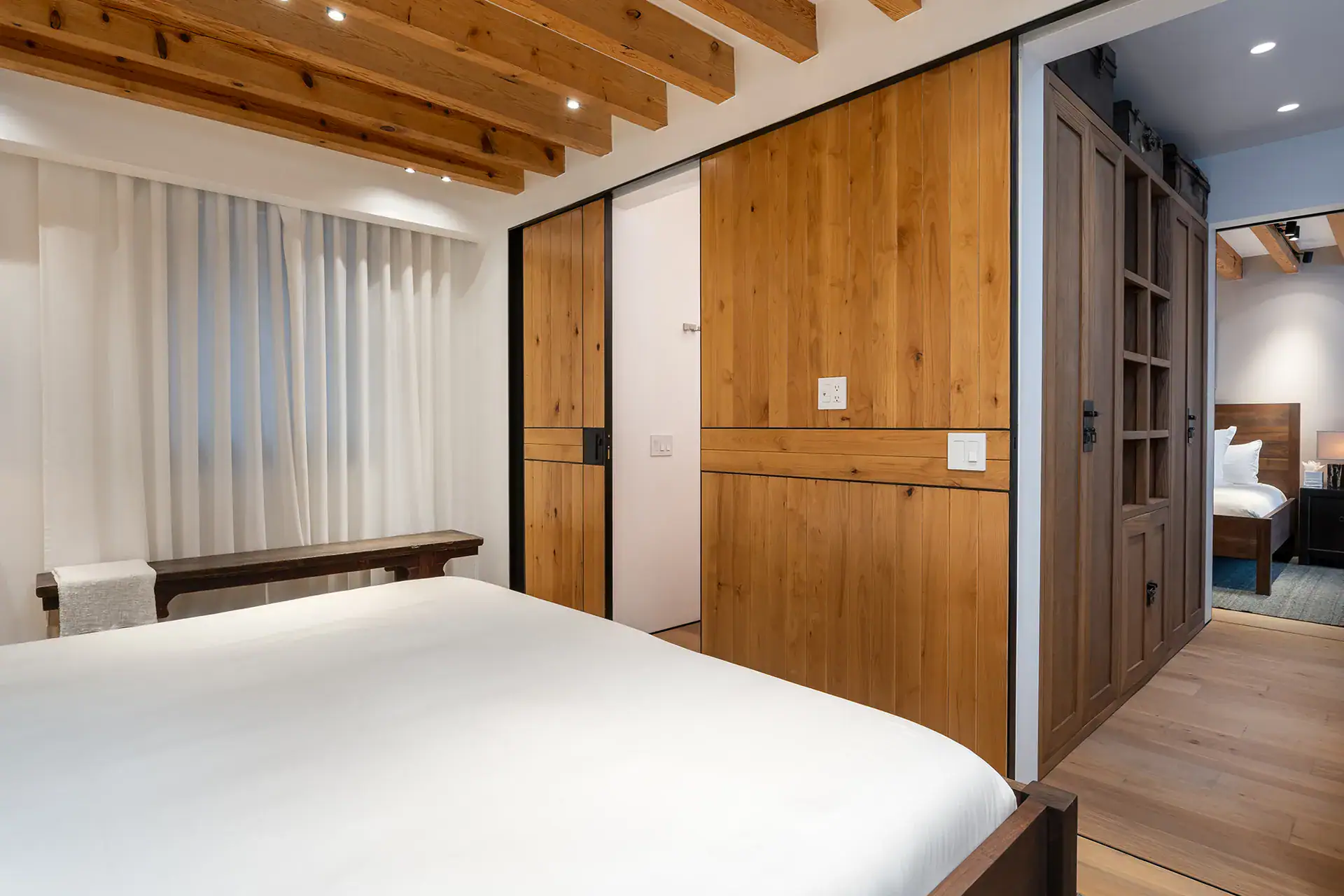 Villa del Parque Central, bedroom with a white bed and wood sliding doors leading to a second room, San Miguel de Allende