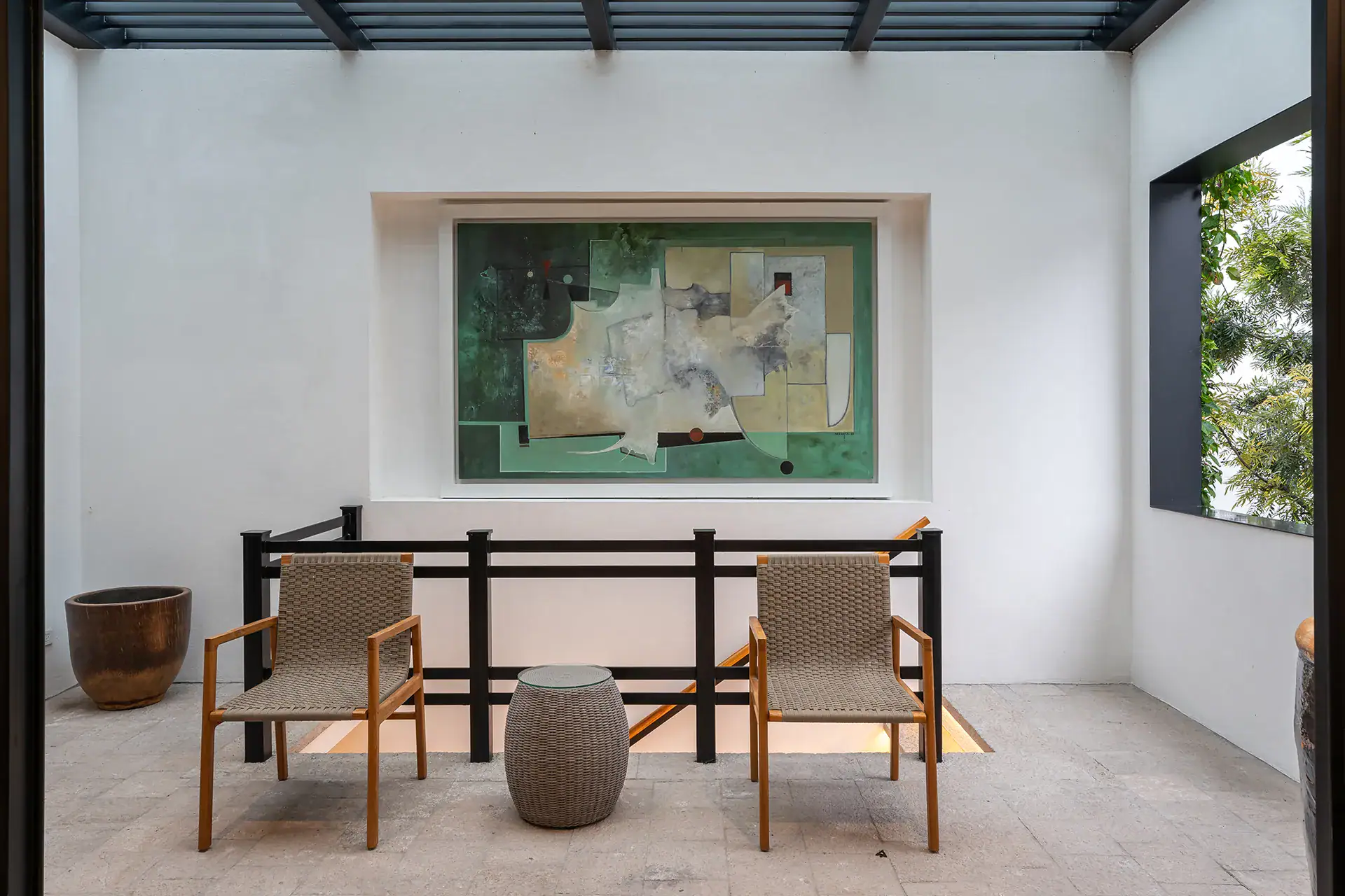 Villa del Parque Central, balcony sitting area with two woven chairs below a large green abstract painting, San Miguel de Allende