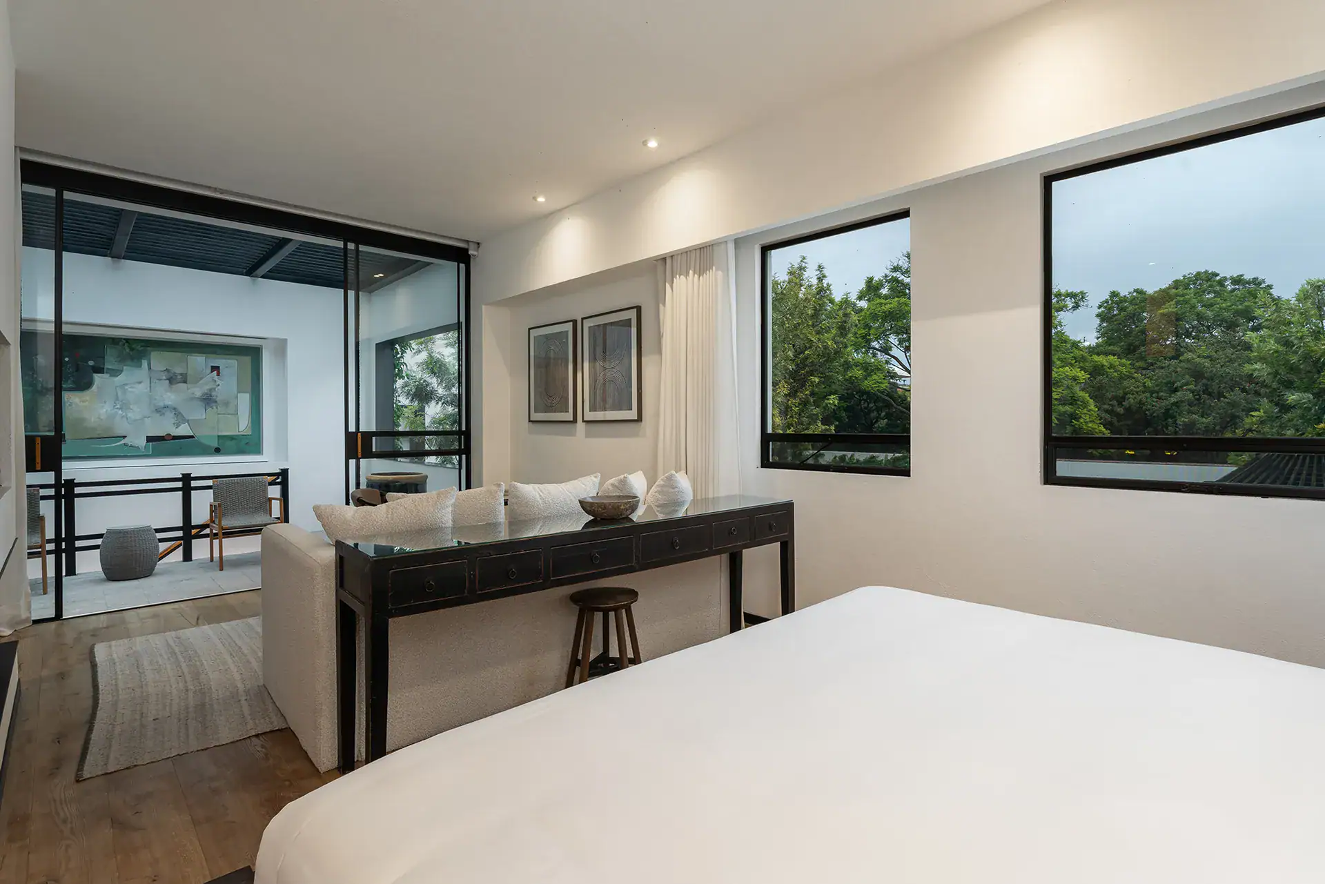 Villa del Parque Central, bedroom with a white bed, console table and view to a glass-enclosed balcony, San Miguel de Allende