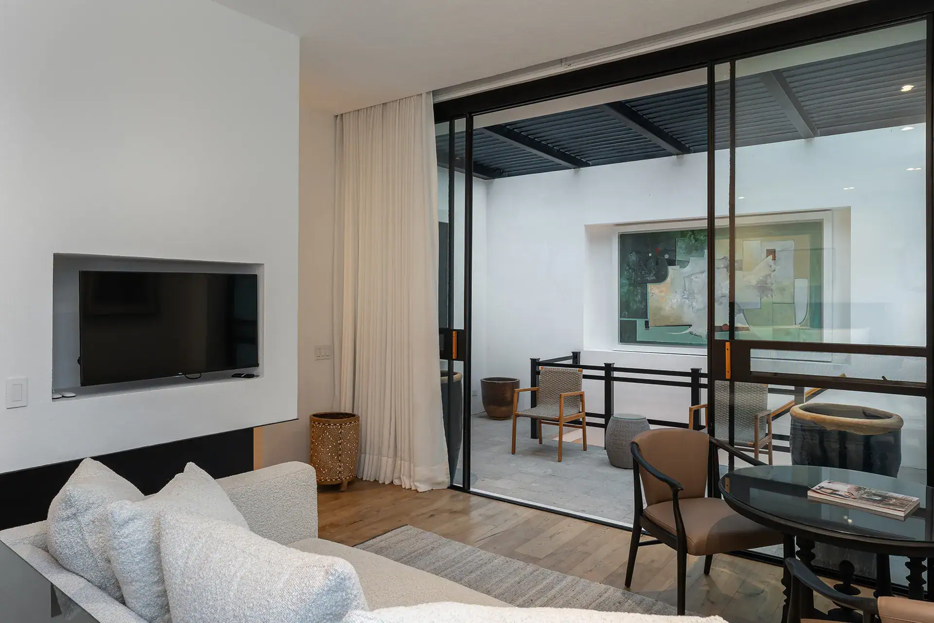 Villa del Parque Central, sitting room with wall-mounted television and sliding glass doors to a balcony, San Miguel de Allende