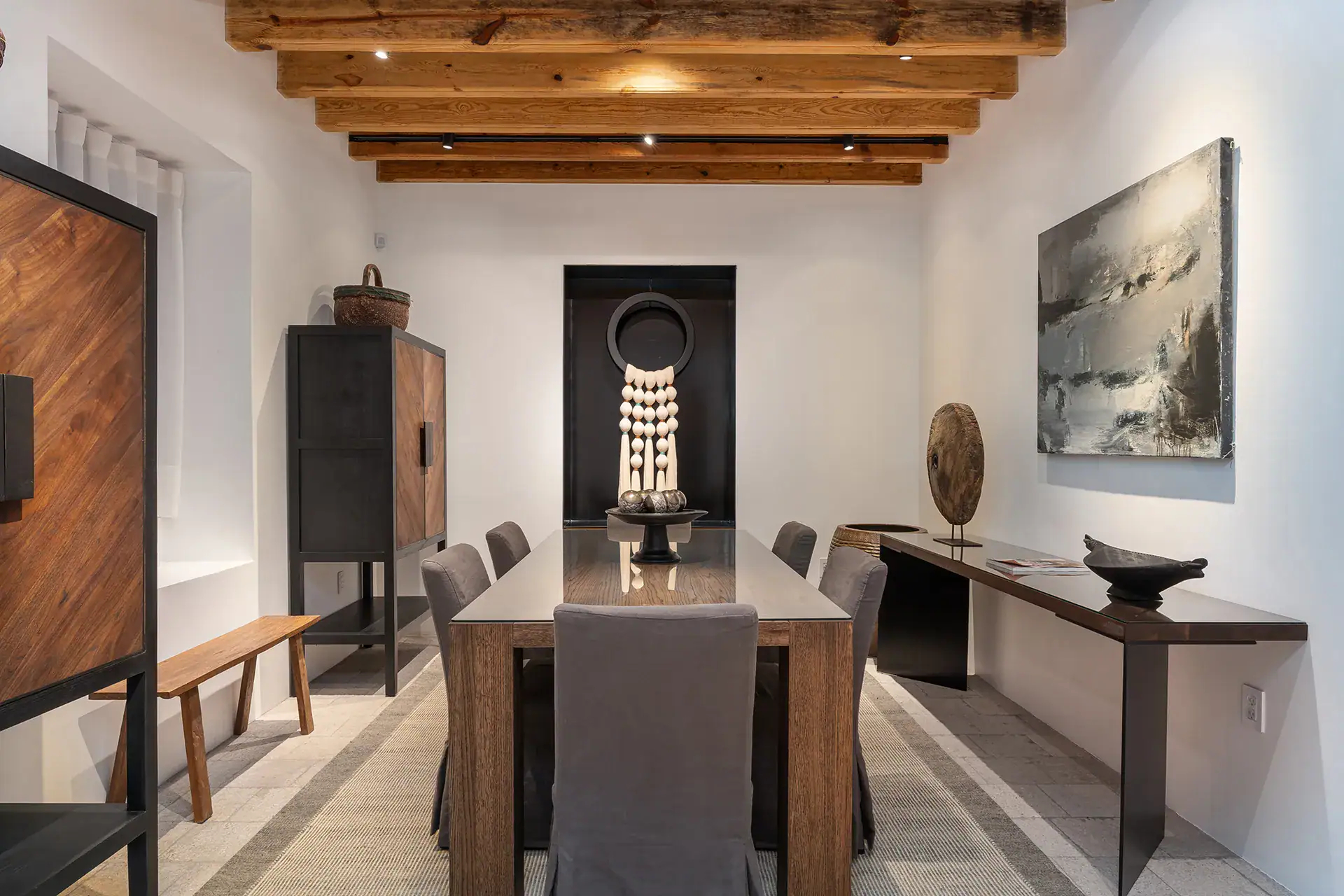 Villa del Parque Central, dining room with a long wood table, gray chairs and tall cabinets under a beamed ceiling, San Miguel de Allende