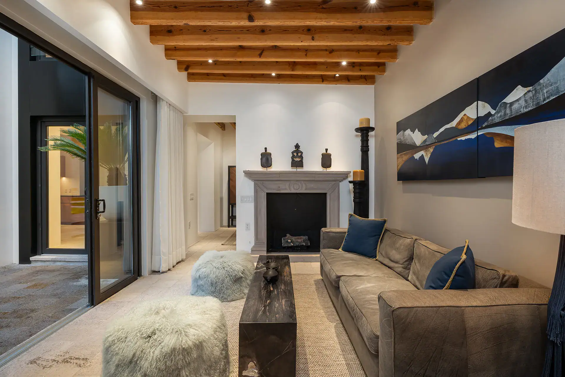 Villa del Parque Central, living room with a stone fireplace, leather sofa and sliding glass doors under a beamed ceiling, San Miguel de Allende